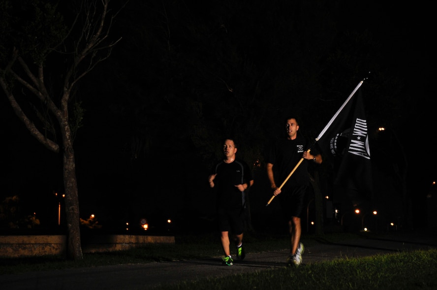 Members from the 82nd Reconnaissance Squadron run throughout the night while holding the Prisoners of War and Missing in Action flag during the POW/MIA 24-hour Vigil Run at Marek Park on Kadena Air Base, Japan, Sept. 19, 2014. Various groups and squadrons across Team Kadena signed up for a designated time slot to run during the event. (U.S. Air Force Photo by Staff Sgt. Darnell T. Cannady/Released) 