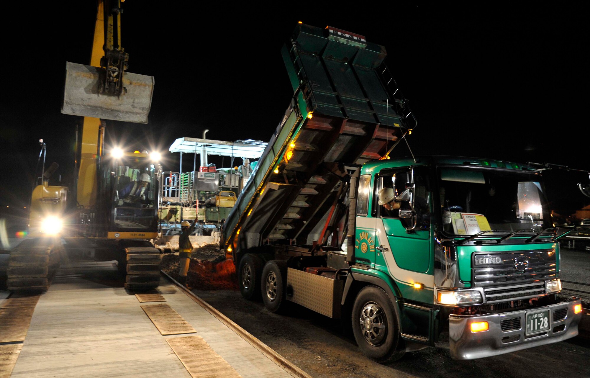 Contractors from the 35th Civil Engineer Squadron unload wet cement onto the runway at Misawa Air Base, Japan, Aug. 19, 2014. Construction on the runway takes place during the early hours of the morning to avoid flying operations. (U.S. Air Force photo by Airman 1st Class Patrick S. Ciccarone/Released)