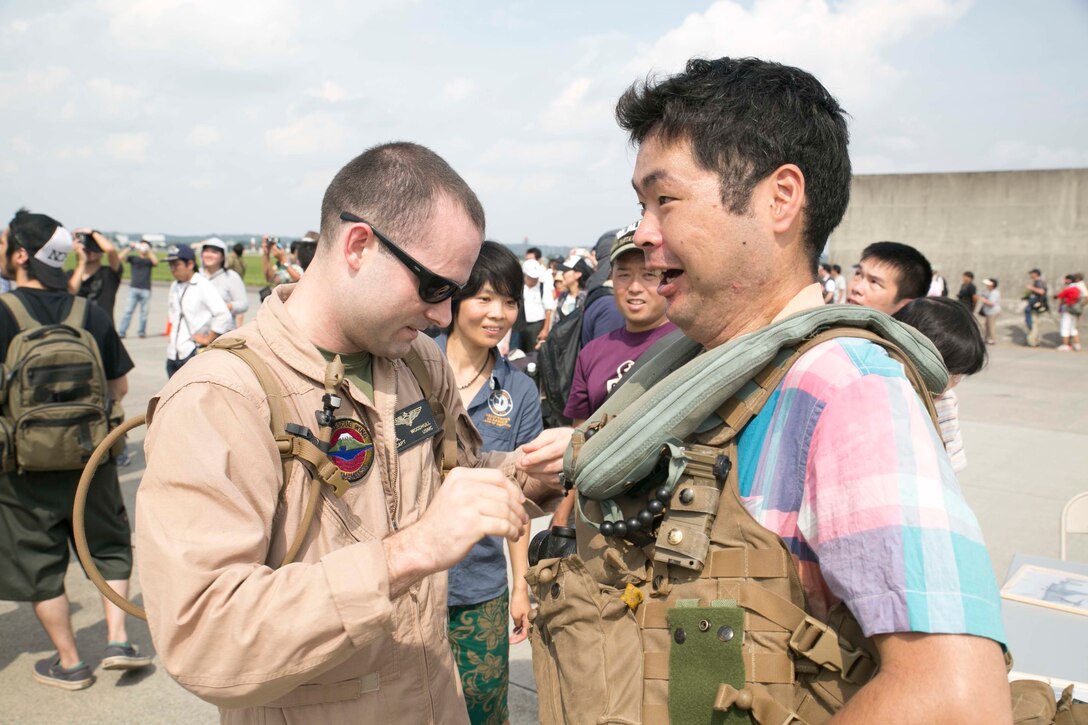 Capt. Seth A. Woodhull, left, from Greenwood, Arkansas, helps an attendee put on aviation equipment at the Japanese-American Friendship Festival Sept. 6 at Yokota Air Base. This year marked the first time the Osprey was displayed at the festival. More than 148,000 people attended the event where the Osprey was one of the most popular aircraft. The festival had aircraft from both the U.S. military and Japan Air Self-Defense Force. Woodhull is the adjutant for Marine Medium Tiltrotor Squadron 265, Marine Aircraft Group 36, 1st Marine Aircraft Wing, III Marine Expeditionary Force. (U.S. Marine Corps Photo by Cpl. Thor J. Larson/Released)
