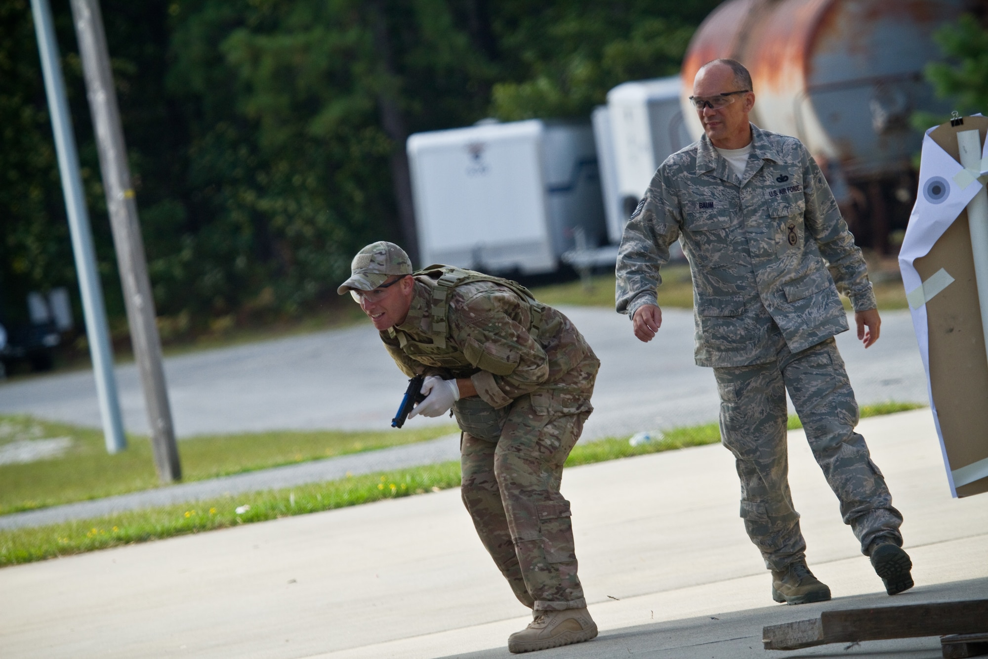 A picture of U.S. Air Force Senior Airman Jake McGrattan preparing to fire sim rounds at targets while being shadowed by Tech. Sgt. Jack Baum.