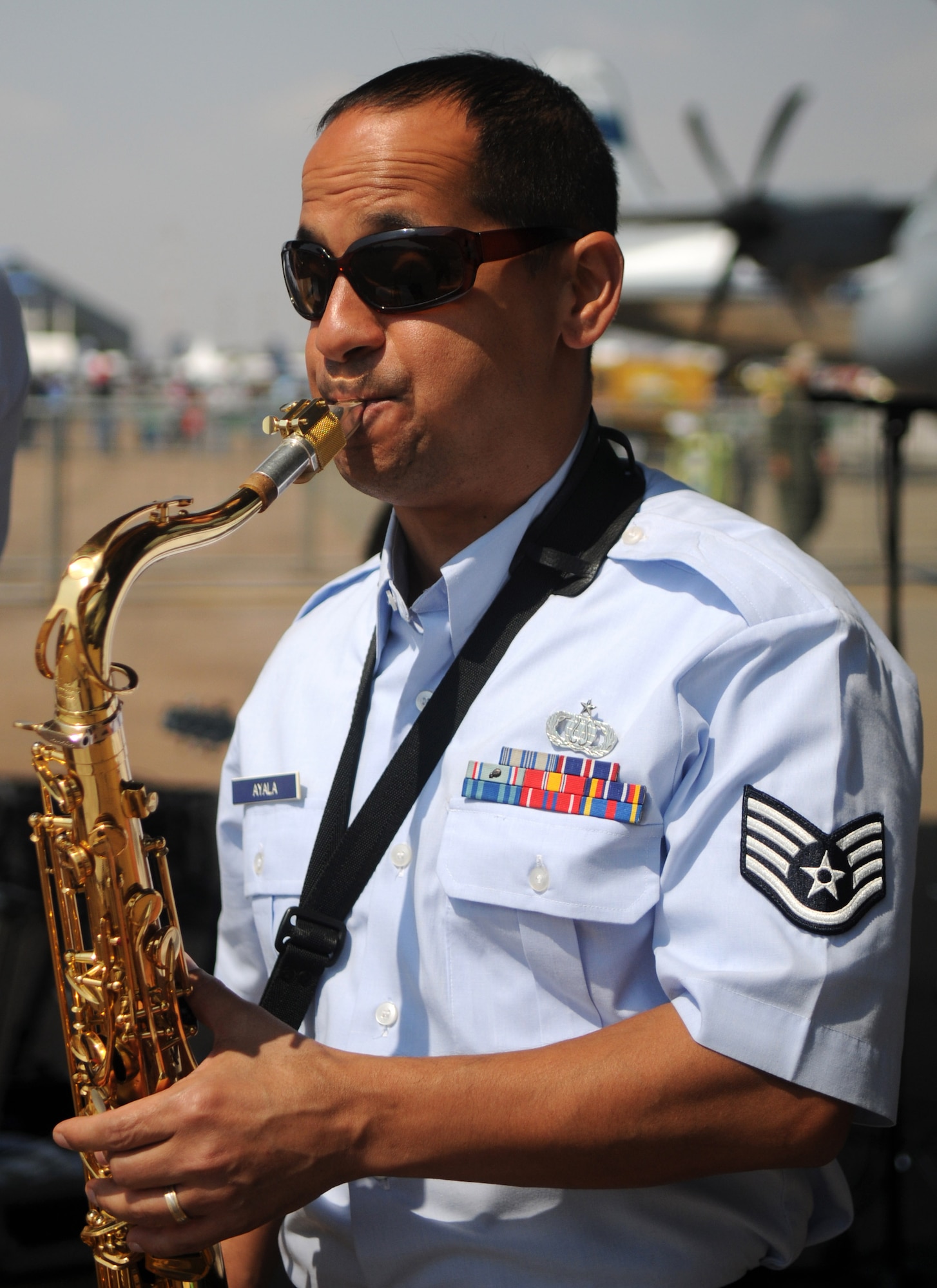 Staff Sgt. Mateo Ayala, saxophonist, and the United States Air Forces in Europe jazz band, Wings of Dixie, perform beneath the wing of a New York Air National Guard C-17 Globemaster III at Africa's largest air show Sept. 20, 2014. A total force team of U.S. Air Force Airmen and U.S. Army Soldiers attended the Africa Aerospace & Defence Expo 2014 at Waterkloof Air Force Base, South Africa, to showcase the United States' commitment to its partnership with South Africa. (U.S. Air Force photo by Tech. Sgt. Austin M. May/Released)