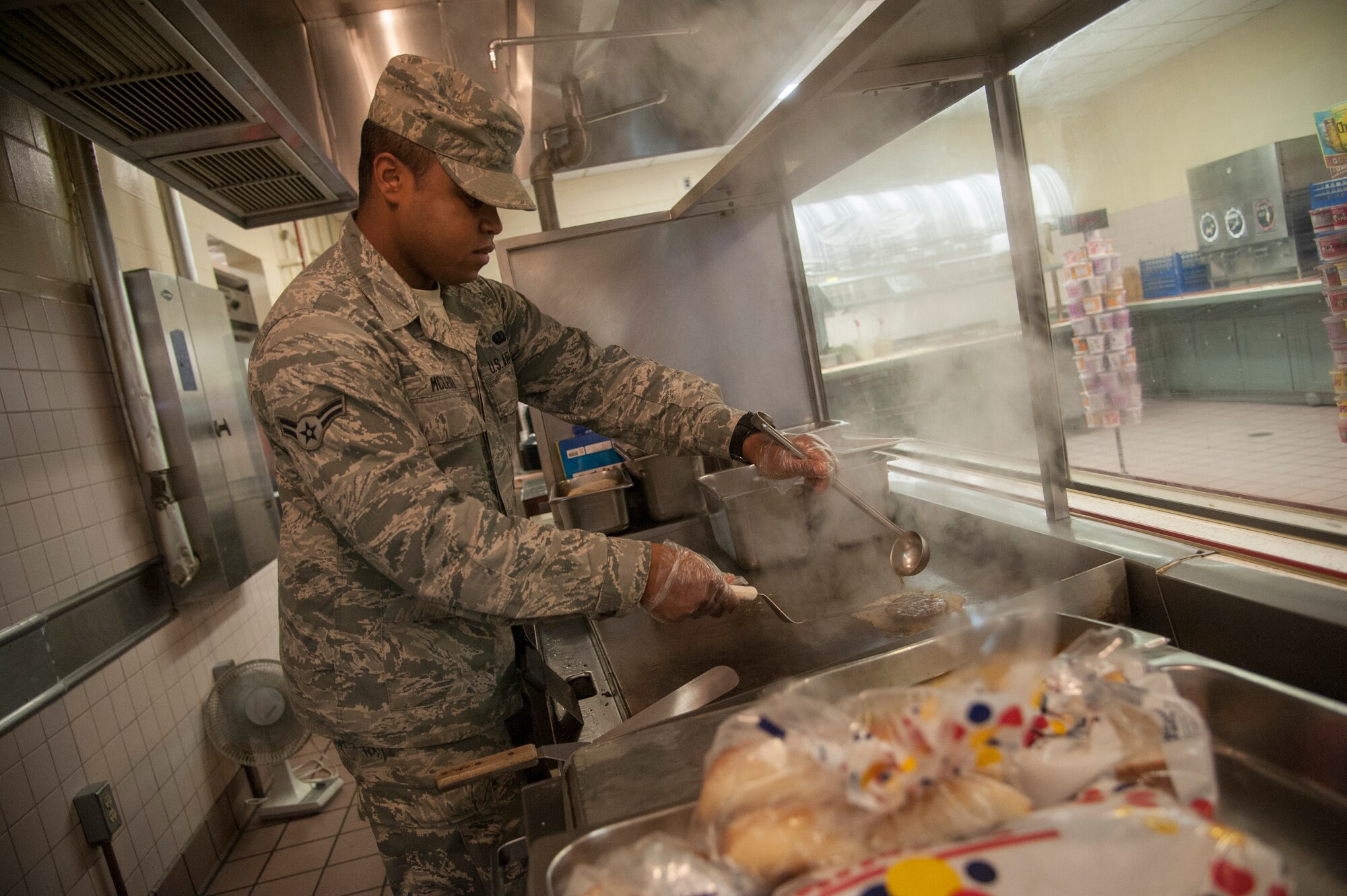 Airman 1st Class Markeese Mcleod, 8th Force Support Squadron food services journeyman, cooks a hamburger during lunch hours at the dining facility at Kunsan Air Base, Republic of Korea, Sept. 16, 2014. More than 2400 people are served daily at the O’Malley Dining Facility. (U.S. Air Force photo by Senior Airman Taylor Curry/Released) ) 