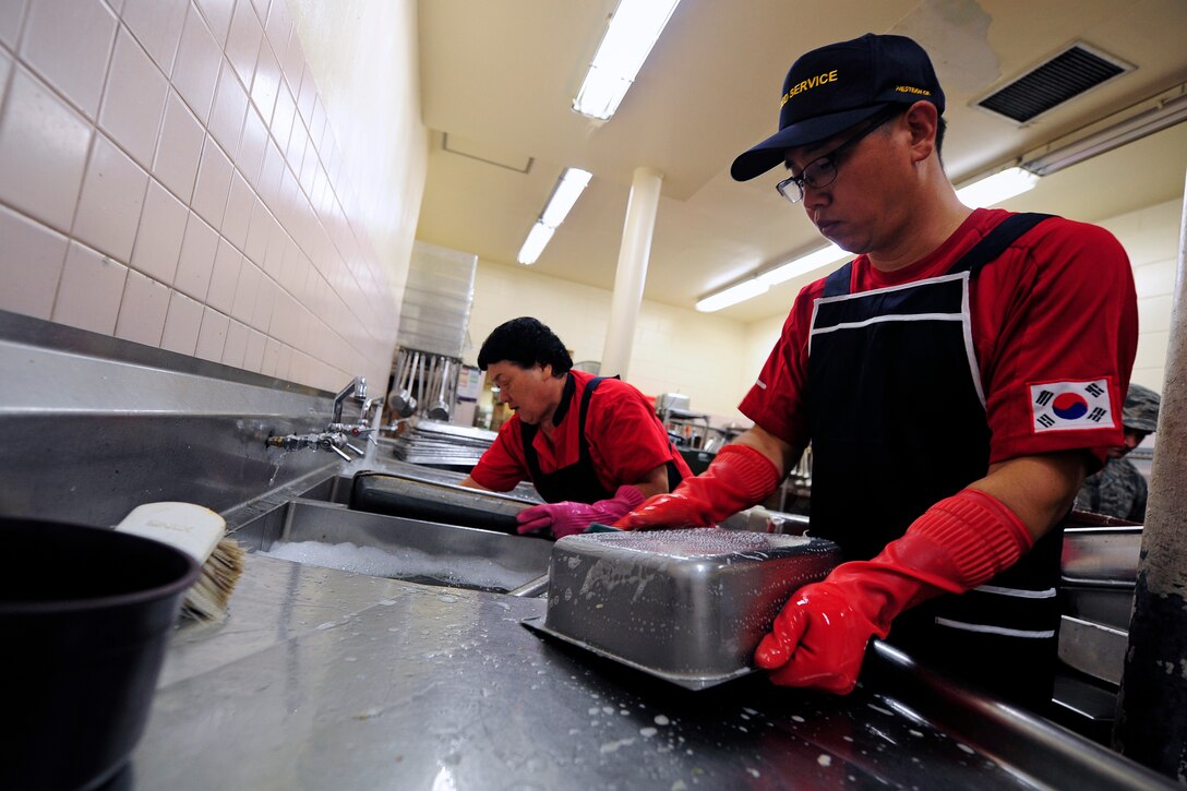Members of the 8th Force Support Squadron dining facility kitchen staff wash food containers during lunch hours at Kunsan Air Base, Republic of Korea, July 10, 2014. The dining facility contracts 51 mess attendants to contribute to the Wolf Pack mission. (U.S. Air Force photo by Senior Airman Taylor Curry/Released) 