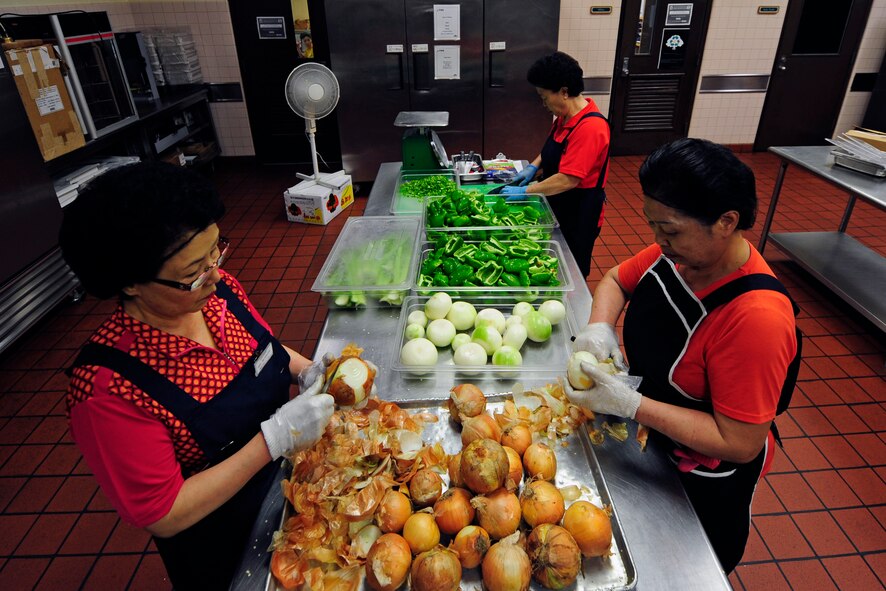 Members of the 8th Force Support Squadron dining facility kitchen staff prepare vegetables before lunch hours at Kunsan Air Base, Republic of Korea, July 10, 2014. The dining facility staff also prepares a variety of other foods including a salad bar, entrees and desserts. (U.S. Air Force photo by Senior Airman Taylor Curry/Released) 