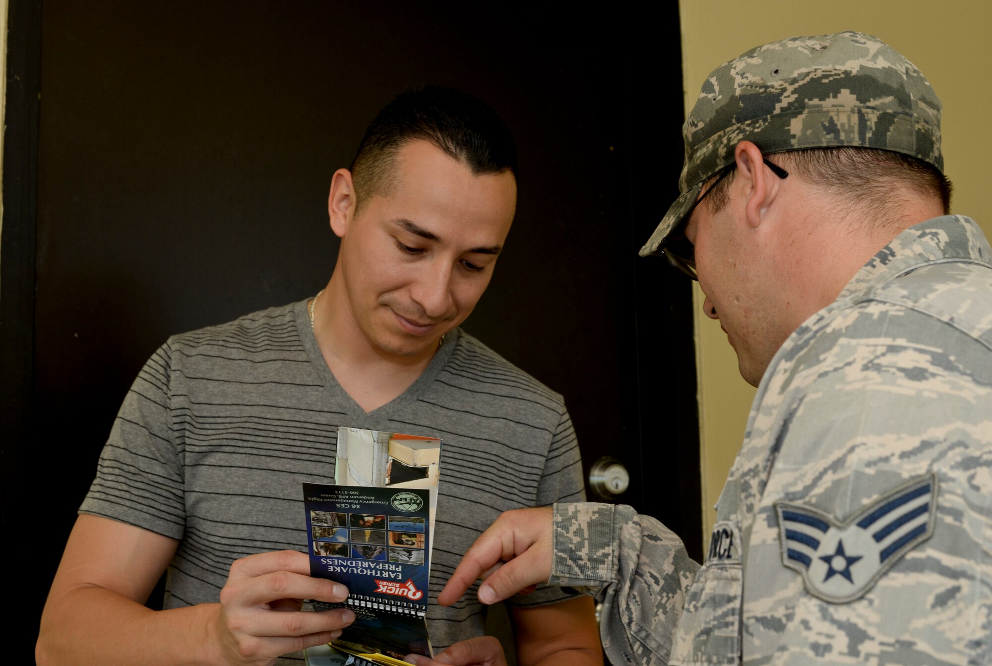 Senior Airman Thomas Hermansen, 36th Civil Engineering Emergency Management Flight, explains information from a tsunami preparedness handbook to U.S. Navy Petty Officer 1st Class Jose Mendez, Naval Communications Station electronics technician, Sept. 12, 2014, on Andersen Air Force Base, Guam. The Airmen went through base housing passing out information about natural disasters for National Preparedness Month. (U.S. Air Force photo by Staff Sgt. Robert Hicks/Released)