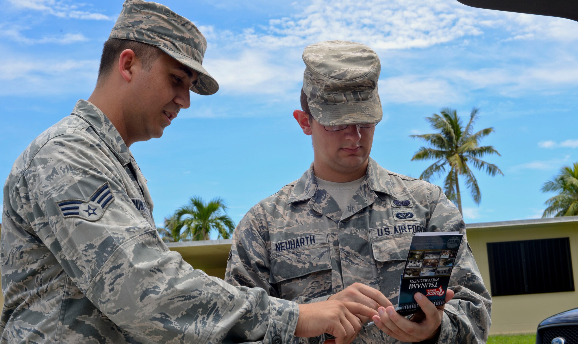 Senior Airman Louie Quintanilla and Airman 1st Class Taylor Neuharth, 36th Civil Engineering Emergency Management Flight, goes over information in a tsunami preparedness handbook Sept. 12, 2014, on Andersen Air Force Base, Guam. The Airmen went through base housing passing out information about natural disasters for National Preparedness Month. (U.S. Air Force photo by Staff Sgt. Robert Hicks/Released)