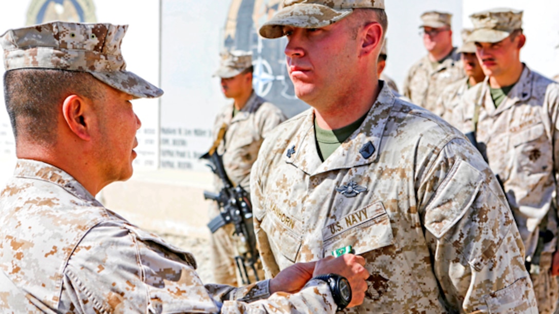 Brigadier Gen. Daniel D. Yoo, left, commander, Regional Command and Marine Expeditionary Brigade – Afghanistan, pins the Navy and Marine Corps Commendation Medal with Combat Distinguishing Device onto Petty Officer 2nd Class Joshua Van Horn, a corpsman with 1st Air Naval Gunfire Liaison Company, during an award ceremony aboard Camp Leatherneck, Afghanistan, Sept. 17, 2014. Van Horn received the award for heroic achievement while being a first responder to Marine casualties after their vehicle struck an improvised explosive device.