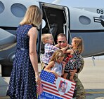 A MC-12W Liberty pilot reunites with his wife and children after returning in the final MC-12 from Kandahar Airfield, Afghanistan, to Beale Air Force Base, Calif., Sept. 22, 2014. Since May 2010 the MC-12W Liberty has supported Operation Enduring Freedom providing real-time intelligence, surveillance, and reconnaissance directly supporting ground forces. (U.S. Air Force photo by Airman 1st Class Ramon A. Adelan/Released)