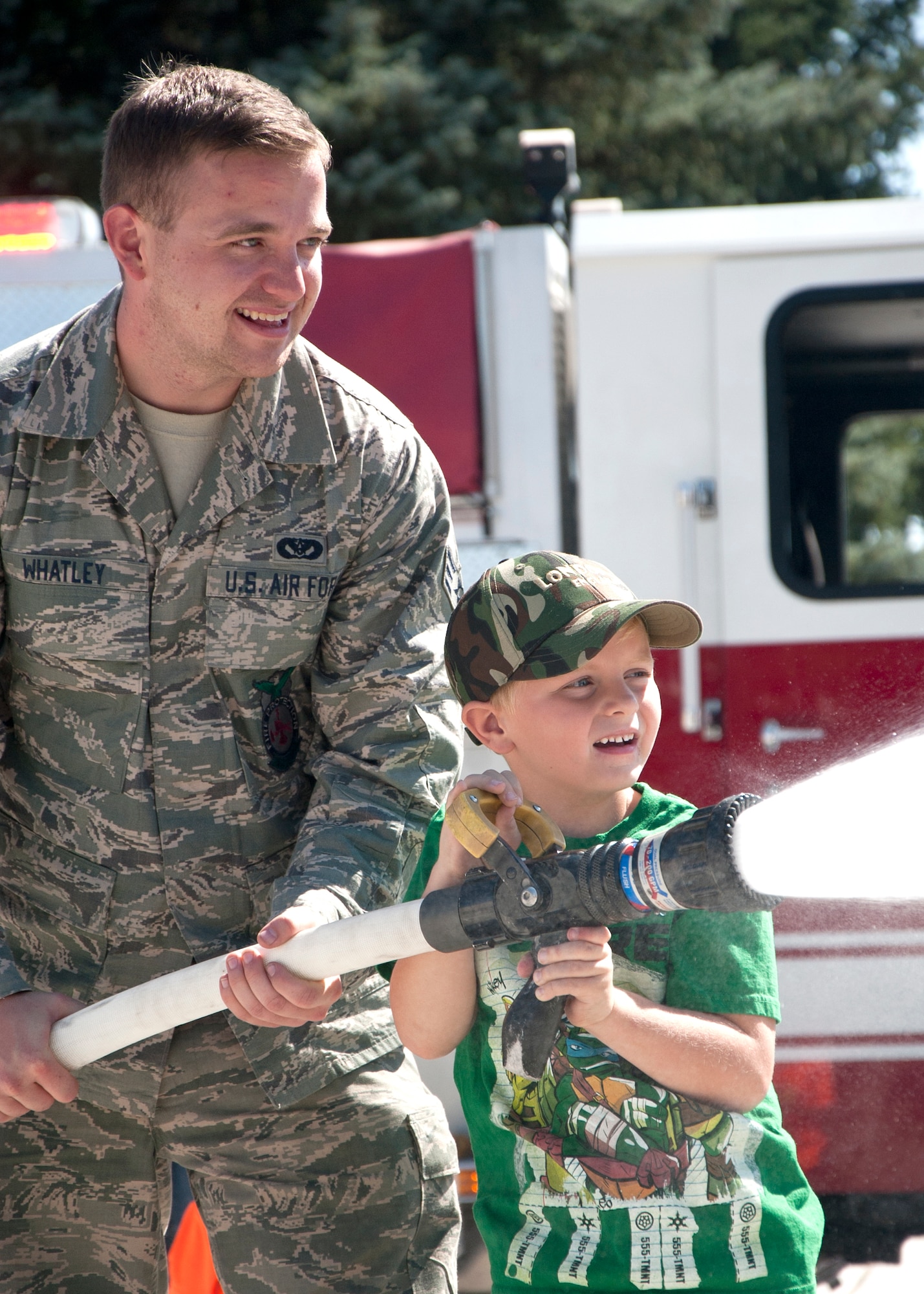 Senior Airman Michael Whatley, 37th Helicopter Squadron, shows Wyatt Hogue, 6, son of Staff Sgt. Andrew Hogue, 790th Missile Security Forces Squadron, how to use a fire hose Sept. 20, 2014, at the Fire Department’s annual open house. (U.S. Air Force Photo by Airman Malcolm Mayfield)