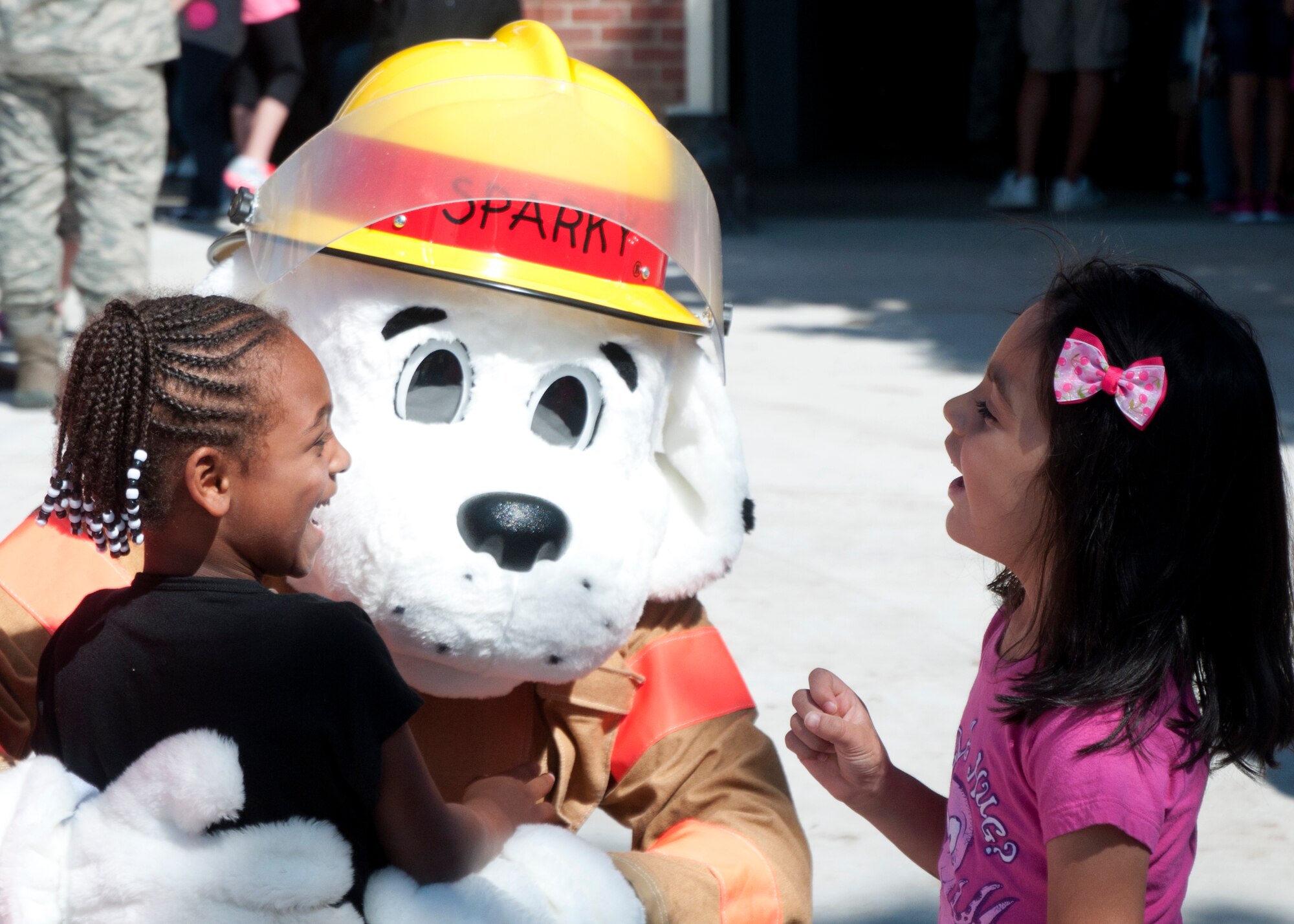 Takiyah Momon, left, 5, daughter of Staff Sgt. Stevie Momon, 90th Missile Maintenance Squadron, and Raquel Guajardo, right, 5, daughter of Senior Airman Miguel Guajardo, 90th Medical Operations Squadron, meet Sparky, the 90th Civil Engineer Squadron’s mascot, Sept. 20, 2014, at the Fire Department’s annual open house. The open house had a turnout of more than 700 individuals, making it the largest open house the Fire Department has held in 20 years. (U.S. Air Force Photo by Airman Malcolm Mayfield)
