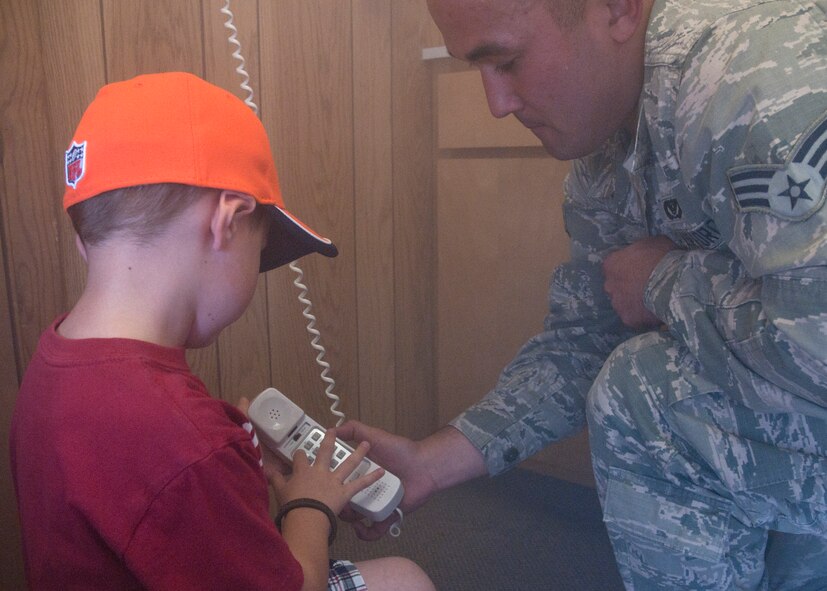 Senior Airman Reid Whittemore, 90th Civil Engineer Squadron, teaches Brennan Fay, 5, son of Tech. Sgt. Jeffrey Fay, 90th Security Forces Squadron, how to call the fire department in case of a fire Sept. 20, 2014, at the Fire Department’s annual open house. The Fire Department’s open house is to kick off the Fire Prevention Week in October. The Fire Prevention Week theme changes every year with this year focusing on smoke alarms. (U.S. Air Force Photo by Airman Malcolm Mayfield)