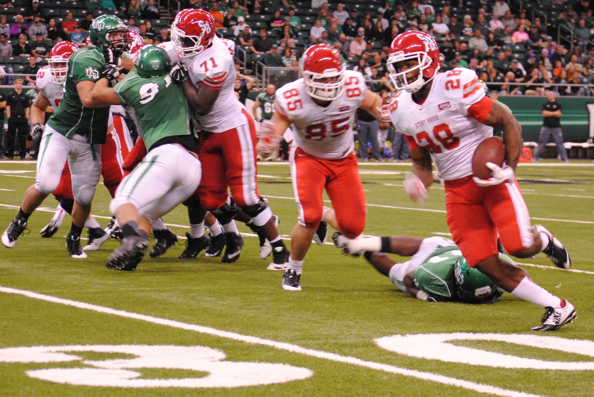 Stony Brook University Seawolves running back James  Kenner turns the corner as he races past University of North Dakota defenders for a first down during the second half of this year’s UND Military Appreciation Day college football game, Sept. 20, 2014, at the Alerus Center in Grand Forks, N.D. The Seawolves lost to UND 13 to 3. (U.S. Air Force photo/Staff Sgt. Luis Loza Gutierrez)

