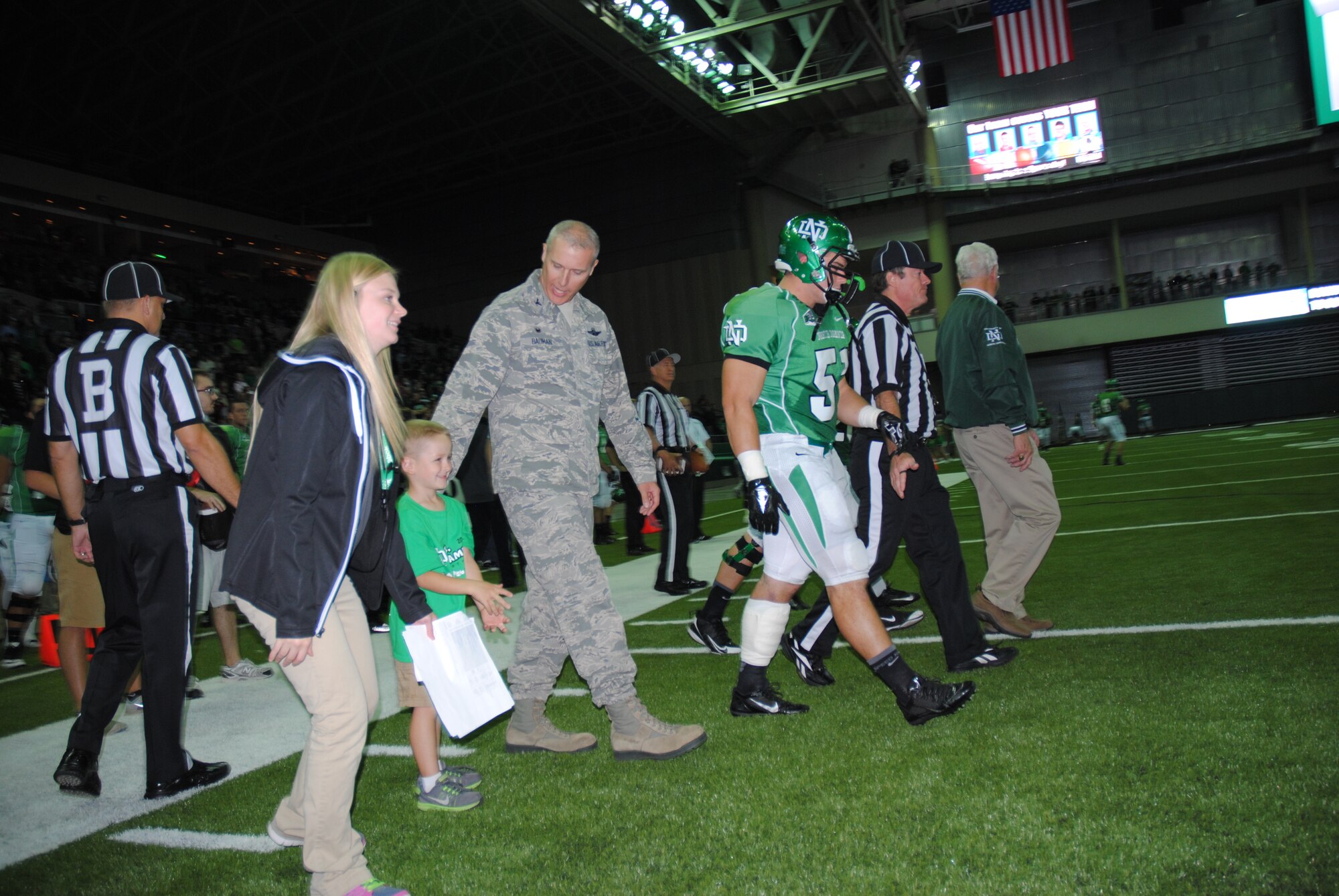 Col. Paul Bauman, 319th Air Base Wing commander, walks onto the center of the football field to observe the coin toss, Sept. 20, 2014, at the Alerus Center in Grand Forks, N.D. Bauman was one of two honorary team captains for the University of North Dakota football game against Stony Brook University. Military members and their families were treated with a free tailgate party meal and free tickets to the game as part of the 17th Annual Maury Rothkopf Military Appreciation Day sponsored by the University of North Dakota and the Grand Forks and East Grand Forks, Minn., Chambers of Commerce. (U.S. Air Force photo/Staff Sgt. Luis Loza Gutierrez)
