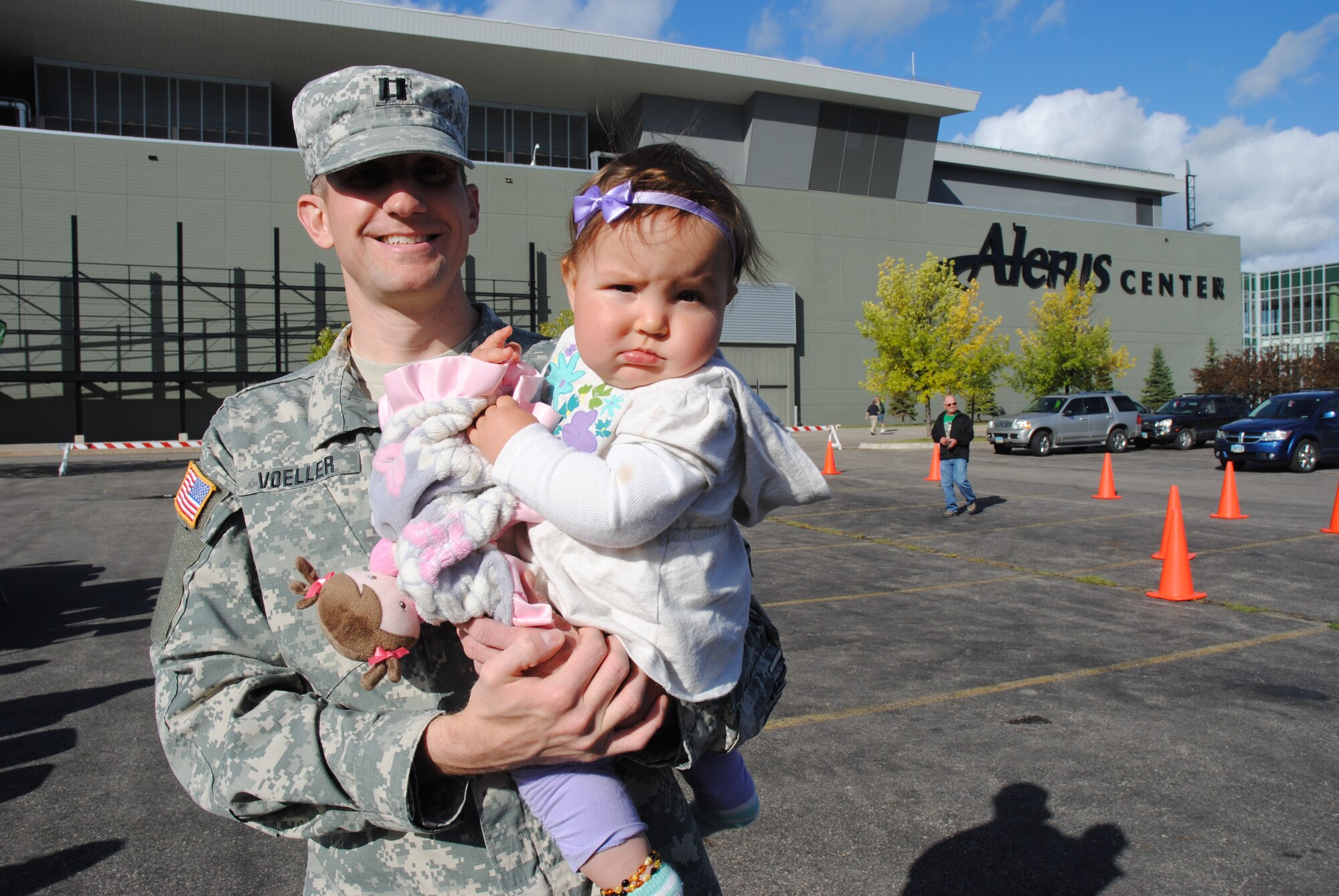 North Dakota Army National Guard Capt. Matt Voeller and his baby daughter Natalie pose for a photo by the Alerus Center during pre-game festivities during this year’s University of North Dakota Military Appreciation Day football game Sept. 20, 2014. Military members and their families were treated to a free meal and free tickets to the a college football game as part of Military Appreciation Day sponsored by the University of North Dakota and the Grand Forks and East Grand Forks, Minn., Chambers of Commerce. (U.S. Air Force photo/Staff Sgt. Luis Loza Gutierrez)
