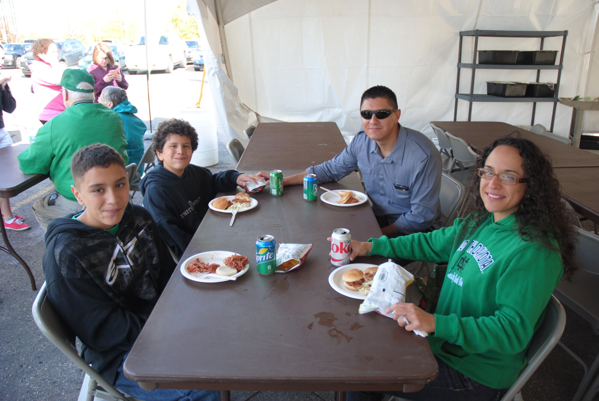 At right, Grand Forks Air Force Base, N.D., members Master Sgt. Raul Lopez and his wife Tech. Sgt. Crystal Lopez enjoy a free barbecue brisket meal with their sons, Noah and Isaiah, during a free tailgate party at the Alerus Center Tailgate Village in Grand Forks, N.D. Service members and their families were treated to a free meal and college football game as part of the 17th Annual Maury Rothkopf Military Appreciation Day, Sept. 20, 2014, which was sponsored by the University of North Dakota and the Grand Forks and East Grand Forks, Minn., Chambers of Commerce. (U.S. Air Force photo/Staff Sgt. Luis Loza Gutierrez)
