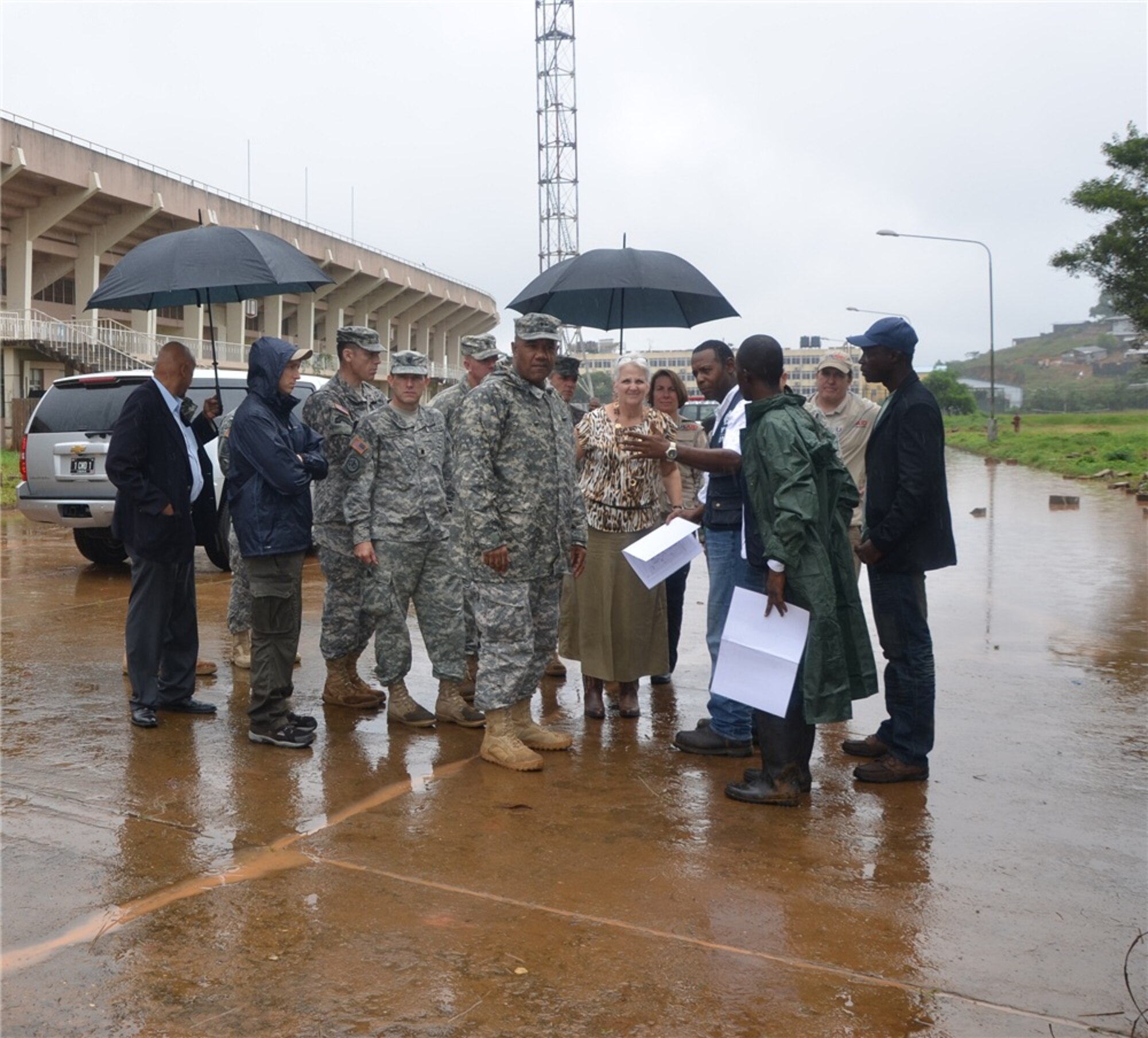 Major General Darryl Williams and U.S. Ambassador Deborah Malac (left to right under the umbrella) speak to Project Superintendent, James Nebleeh, at Samuel K. Doe stadium, where an Ebola Treatment Unit (ETU) is being constructed. More personnel and supplies, are expected to arrive in Monrovia in the coming days.