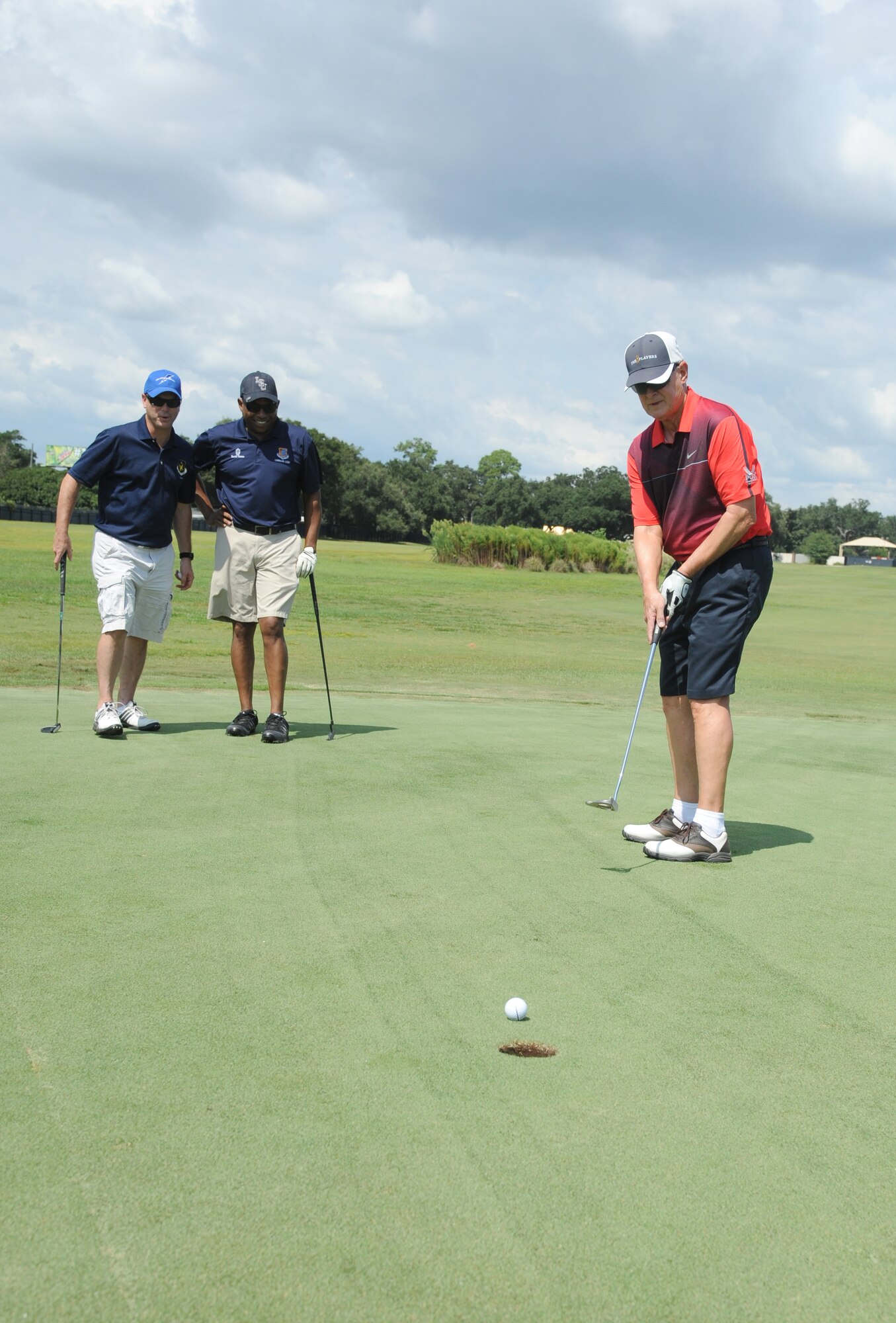 Chief Master Sgts. David Staton, 2nd Air Force command chief, and Farrell Thomas, 81st Training Wing command chief, watch retired Col. Bob Neal putt the ball into hole number 4 during the Don Wylie Memorial Annual Golf Tournament Sept. 19, 2014, at the Bay Breeze Golf Course, Keesler Air Force Base, Miss.  Keesler defeated the Biloxi Bay Chamber. (U.S. Air Force photo by Kemberly Groue)