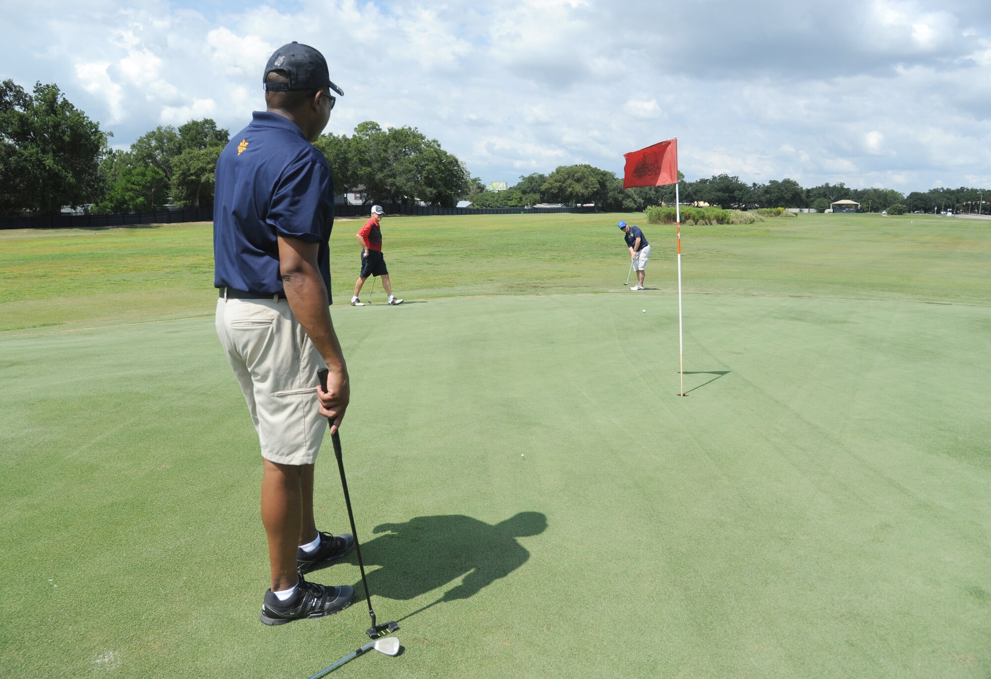 Chief Master Sgt. Farrell Thomas, 81st Training Wing command chief, and retired Col. Bob Neal, stands by as Chief Master Sgt. David Staton, 2nd Air Force command chief, putts on hole number 4 during the Don Wylie Memorial Annual Golf Tournament Sept. 19, 2014, at the Bay Breeze Golf Course, Keesler Air Force Base, Miss.  Keesler defeated the Biloxi Bay Chamber. (U.S. Air Force photo by Kemberly Groue)