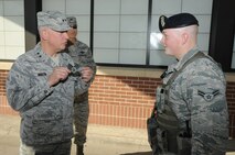 Maj. Gen. Frederick Martin, U.S. Air Force Expeditionary Center commander, presents Senior Airman stripes to Airman 1st Class Sean Egan, 319th Security Forces Squadron alarm monitor, at the main gate on Grand Forks Air Force Base, N.D., Sept. 19, 2014. Egan was promoted to Senior Airman Below-the-Zone and received his new stripes after welcoming Martin onto the installation for the Air Force Ball. (U.S. Air Force photo/Staff Sgt. David Dobrydney)