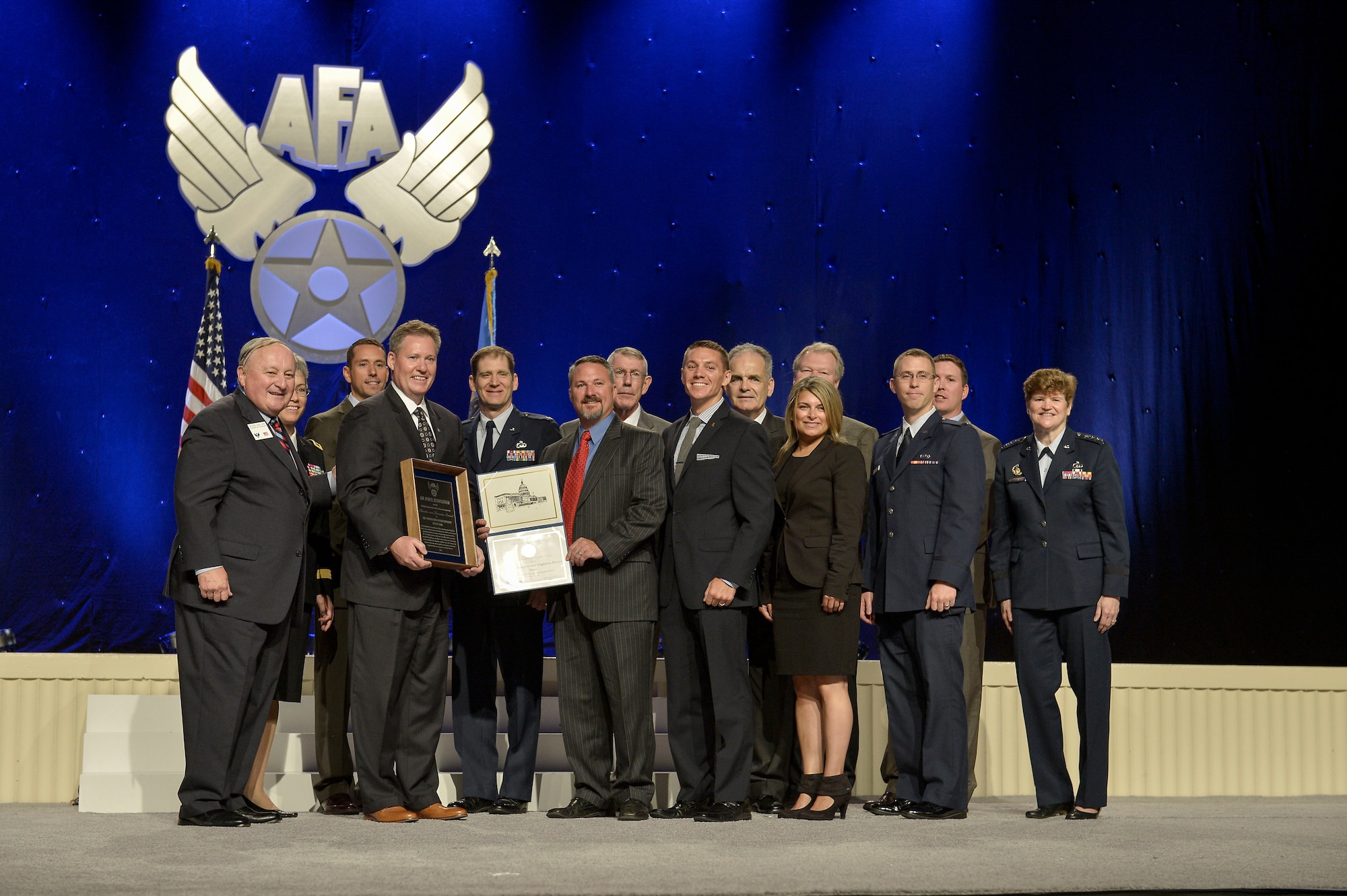Members of the Counter-Improvised Explosive Device team from Hanscom Air Force Base, Mass., receive the Theodore von Karman Award during the 2014 Air Force Association's Air and Space Conference Award Ceremony in National Harbor, Md., Sept 15. On stage hoding a certificate is U.S. Air Force Maj. Tim Helfrich, a military Congressional fellow assigned to the office of Rep. Niki Tsongas (MA-D) office and Gen. Janet Wolfenbarger, far right, Air Force Life Cycle Management Center commander. The award is given to those who have made significant contributions to national defense in the field of science and engineering. (U.S. Air Force photo by Staff Sgt. Anthony Nelson Jr.)
