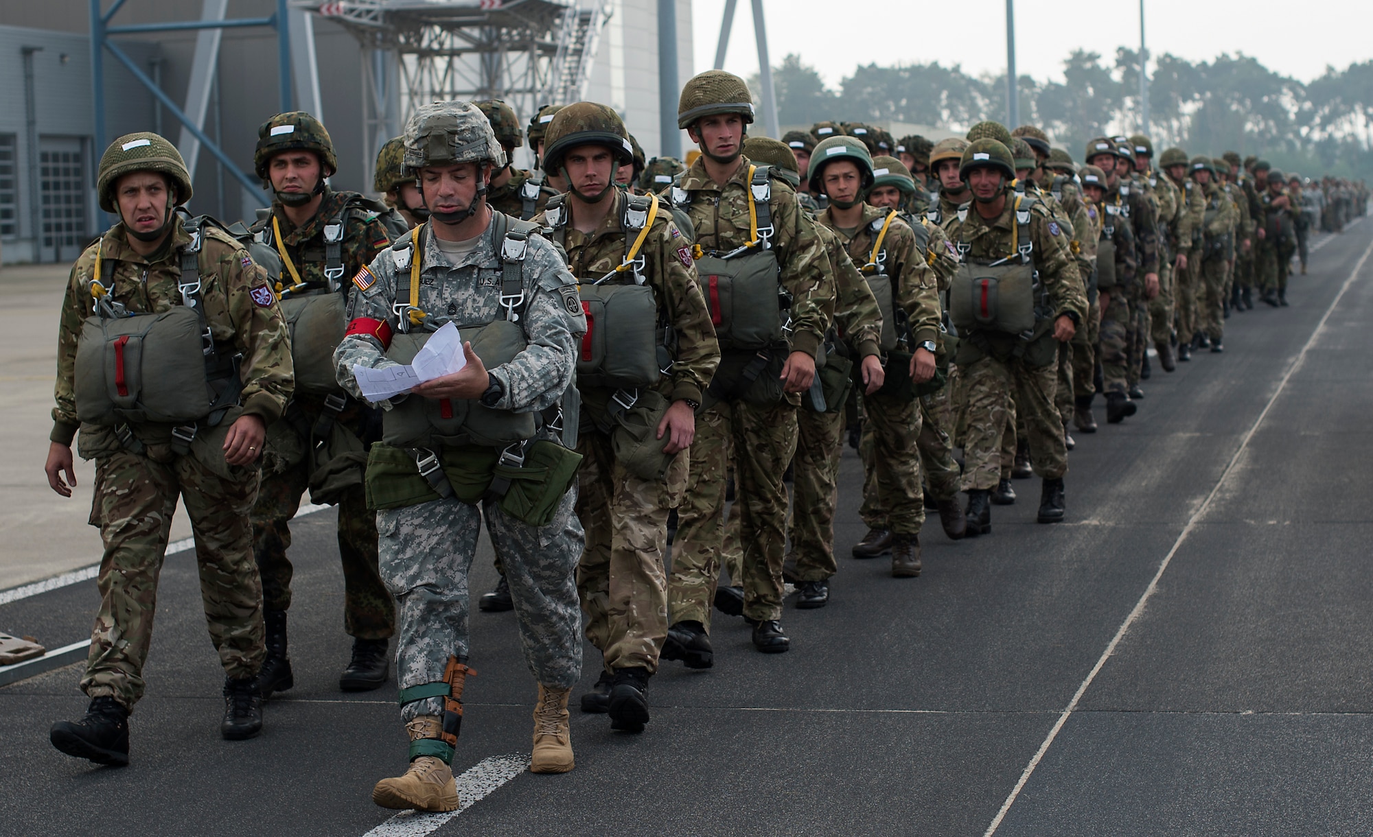 U.S. Army Sergeant 1st Class Luis R. Rodriguez, 82nd Airborne Division U.S. Army Advance Airborne School senior instructor, leads paratroopers to their aircraft Eindhoven, Netherlands, Sept. 20, 2014. Paratroopers from eight nations came to the Netherlands to reenact the jumps made during Operation Market Garden 70 years ago. The commemoration was held to honor those who lost their life to liberate the Netherlands. (U.S. Air Force photo/Senior Airman Damon Kasberg)
