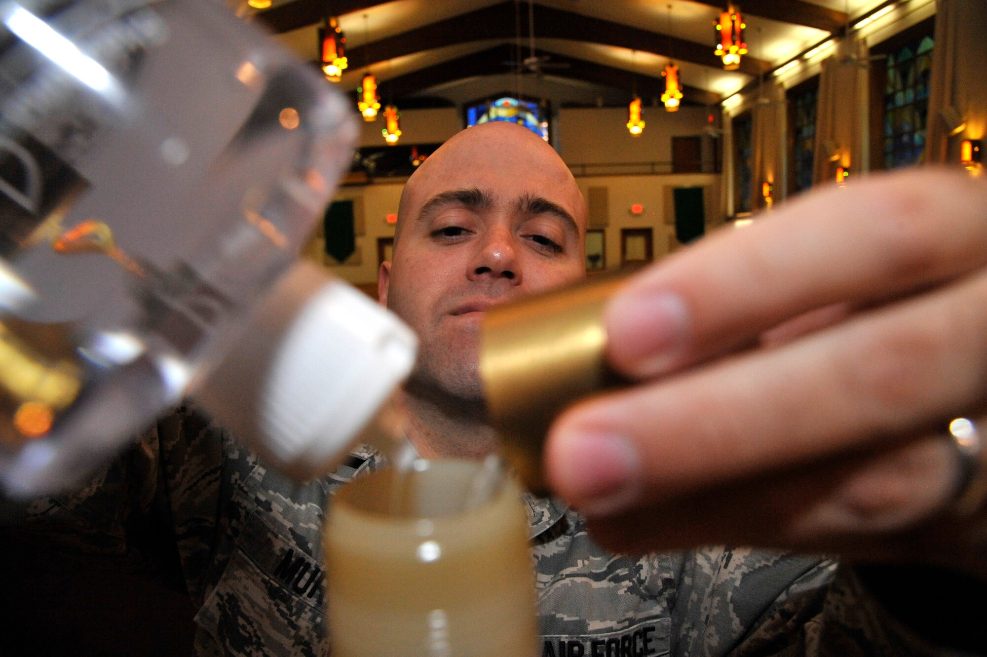 U.S. Air Force Staff Sgt. Ronald Murray, 509th Bomb Wing chaplain assistant, prepares for Mass by filling the altar candles at Whiteman Air Force Base, Mo., Sept. 3, 2014. Chaplain assistants prepare the chapel throughout the week to ensure chaplains are able to conduct their services. (Air Force photo by Airman 1st Class Keenan Berry/Released)