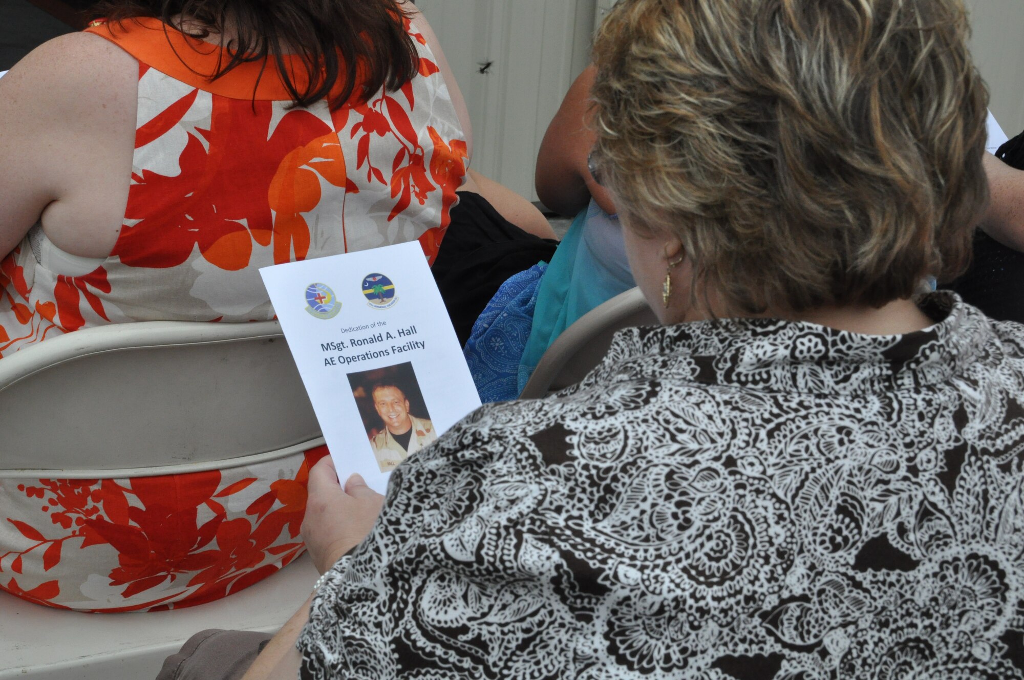 A family member holds a pamphlet honoring Master Sergeant Ron Hall, who spent 24 of his 28 years in the Air Force as a member of the 315th Aeromedical Evacuation Squadron. After years of dedicated service to the military, Hall passed away in May 2011. Family, friends and co-workers attended a dedication ceremony officially naming Building 416 the Master Sergeant Ronald A. Hall Aeromedical Evacuation Operations Facility. Aeromedical Evacuation crews, made up of two nurses and three EMTs, report to the Operations Facility for permission briefs and to preflight their equipment. U.S. Air Force photo by Capt. Michaela Judge)