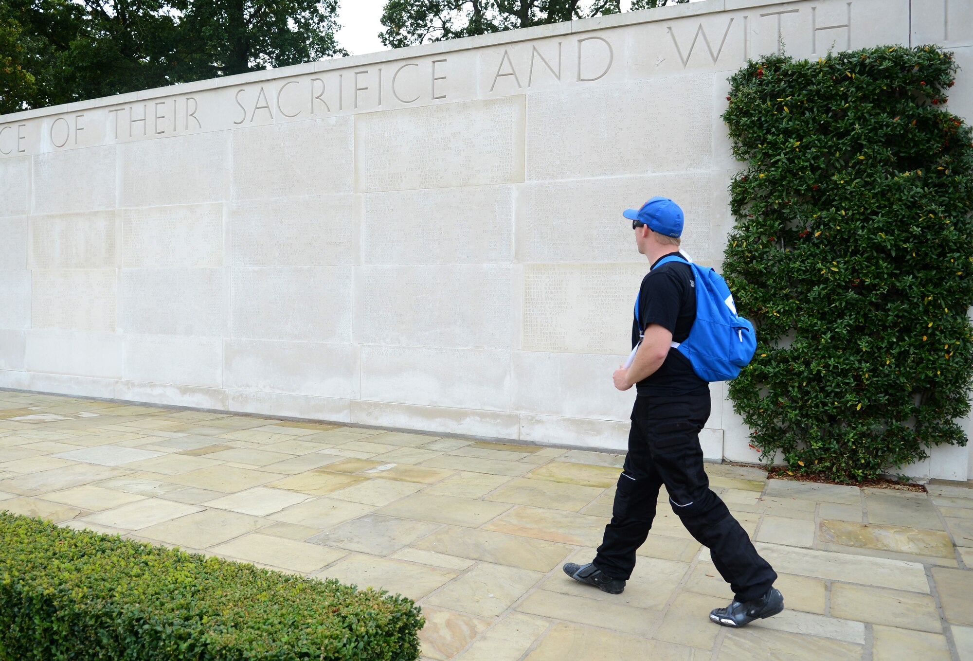 A member of the Rolling Thunder motorcycle rally walks along the Wall of the Missing Sept. 19, 2014, at Madingley American Cemetery, near Cambridge, England. The wall lists the names of 5,127 service members missing in action or who lost their lives without positive identification. (U.S. Air Force photo/Airman 1st Class Dillon Johnston/Released)