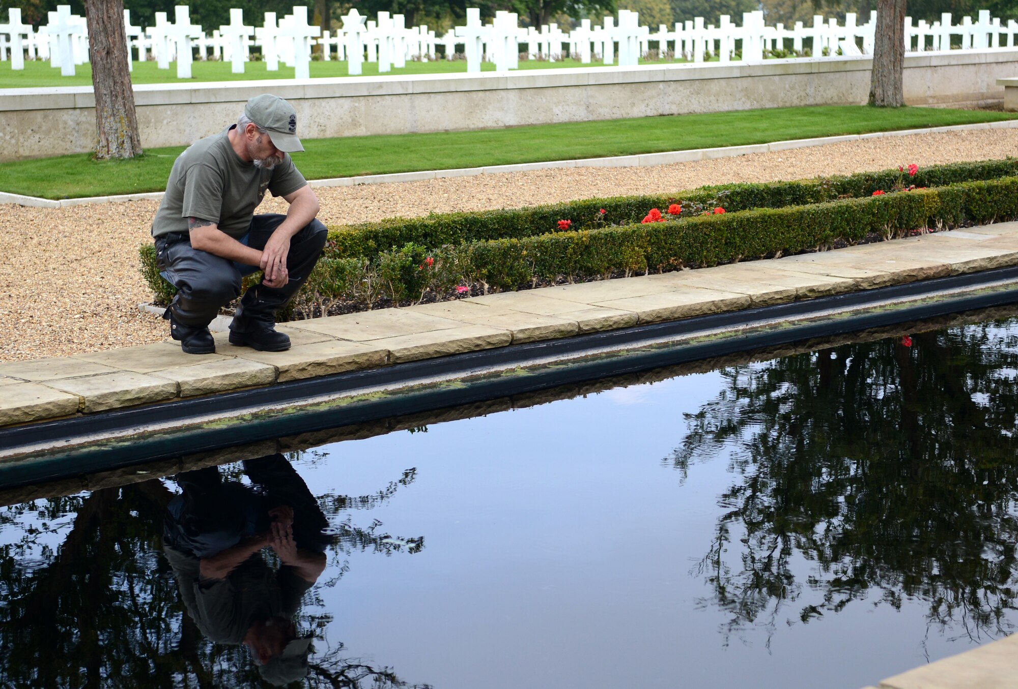 Mike Poston, Rolling Thunder motorcycle rally member, peers into a reflecting pool Sept. 19, 2014, at Madingley American Cemetery, near Cambridge, England. The cemetery holds the remains of 3,812 American service members across more than 30 acres. (U.S. Air Force photo/Airman 1st Class Dillon Johnston/Released)