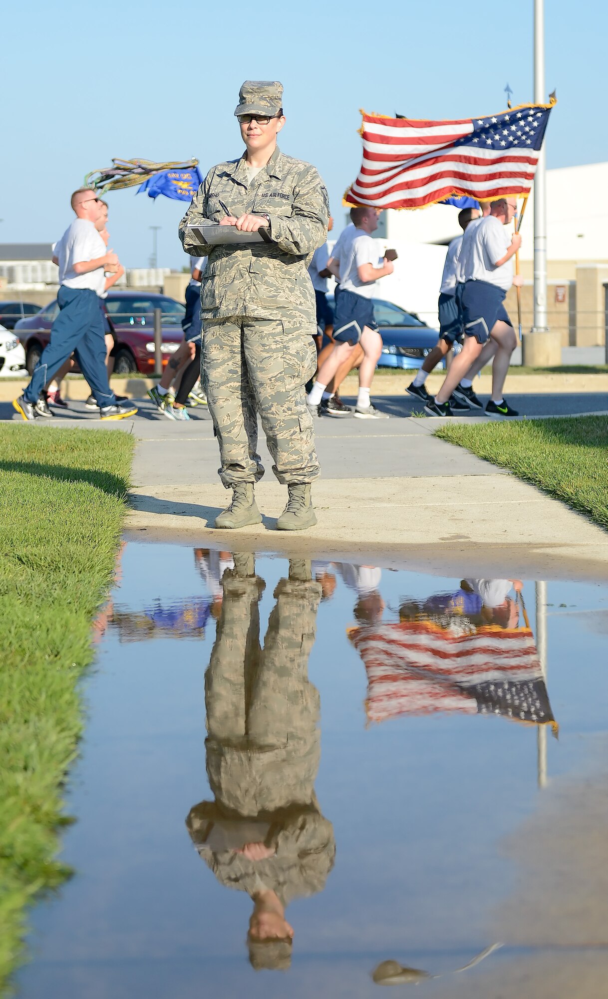 Master Sgt. Brea Misho, 436th Operations Support Squadron first sergeant, holds the master list of participants for the POW/MIA Remembrance Day activities as a group of runner???s passes behind her Sept. 19, 2014, at Dover Air Force Base, Del. Misho is in charge of scheduling participants for the 24 hour run. (U.S. Air Force photo/Greg L. Davis)