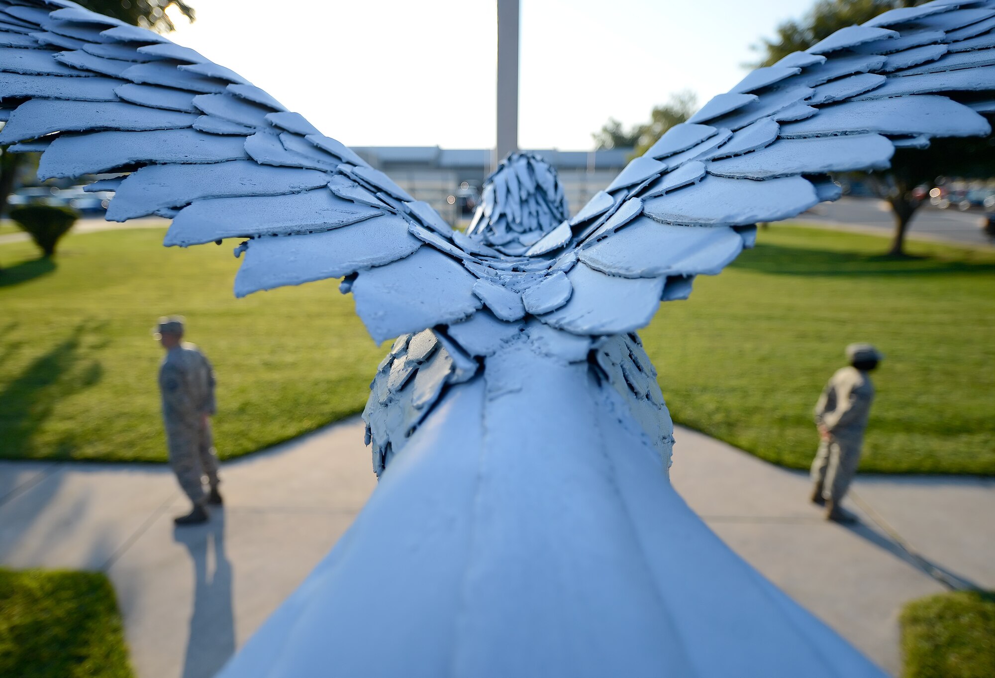 Outstretched wings of an iron eagle frame members of the 436th Airlift Wing as they stand immobile during a POW/MIA Remembrance Day vigil Sept. 19, 2014, at Dover Air Force Base, Del. The 436th AW is known as the 'Eagle Wing' and the eagle statue is hand-crafted from sheet metal over a rebar frame. (U.S. Air Force photo/Greg L. Davis)