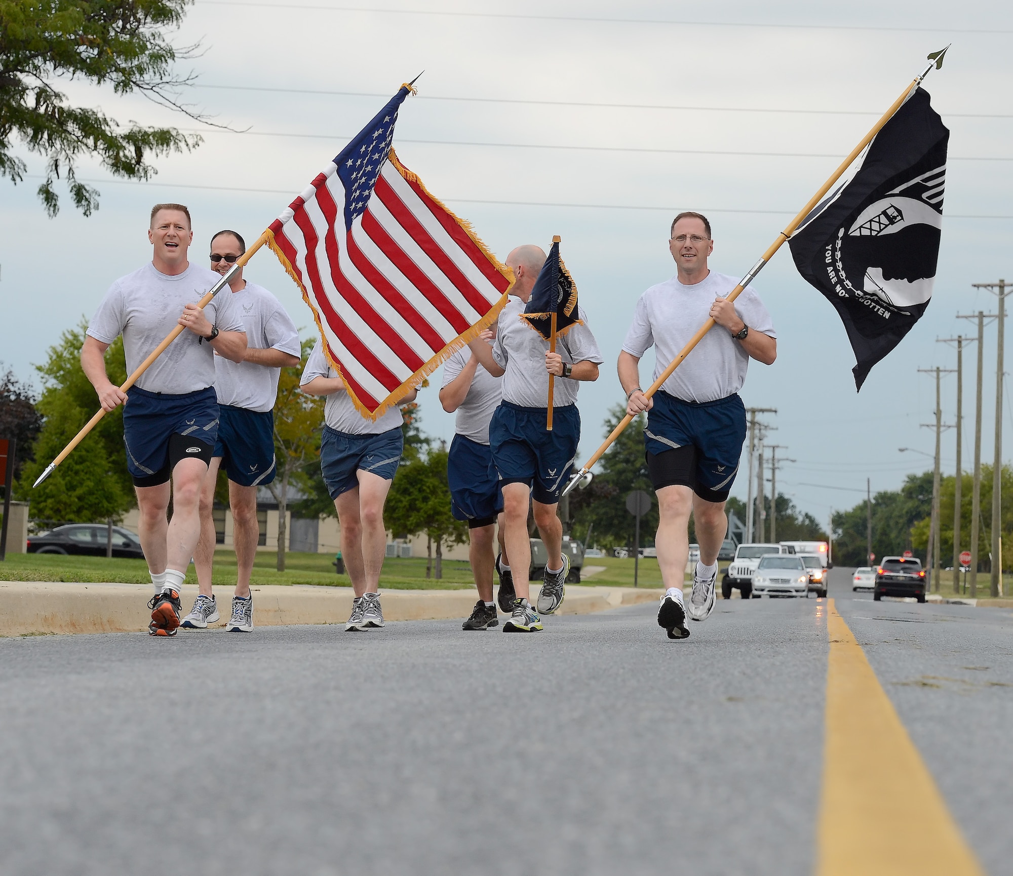 Senior leadership of the 436th Airlift Wing carry the American and POW/MIA flags as they lead a group of runners during the 24 hour POW/MIA memorial run on Sept. 18, 2014, Dover Air Force Base, Del. Col. Michael W. Grismer Jr., 436th AW commander, is shown on the left while Chief Master Sgt. Stanley C. Cadell, 436th AW command chief, is on the right. (U.S. Air Force photo/Greg L. Davis)