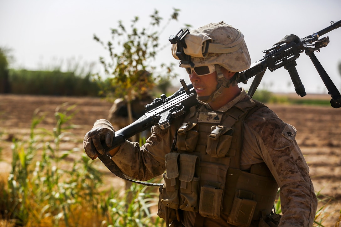 U.S. Marine Corps Cpl. Michael Fort walks through a field with an M240B ...