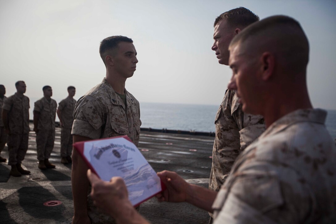 U.S. Marine Corps Cpl. Will Demarest, left, Battalion Landing Team 1st Battalion, 6th Marine Regiment, 22nd Marine Expeditionary Unit (MEU), assault amphibious vehicle crewman and native of Glen Mills, Pa., receives a certificate of commendation as for achieving the title of honor graduate for a corporals course aboard the amphibious dock landing ship USS Gunston Hall (LSD 44). The 22nd MEU is deployed with the Bataan Amphibious Ready Group as a theater reserve and crisis response force throughout U.S. Central Command and the U.S. 5th Fleet area of responsibility. (U.S. Marine Corps photo by Sgt. Austin Hazard/Released)