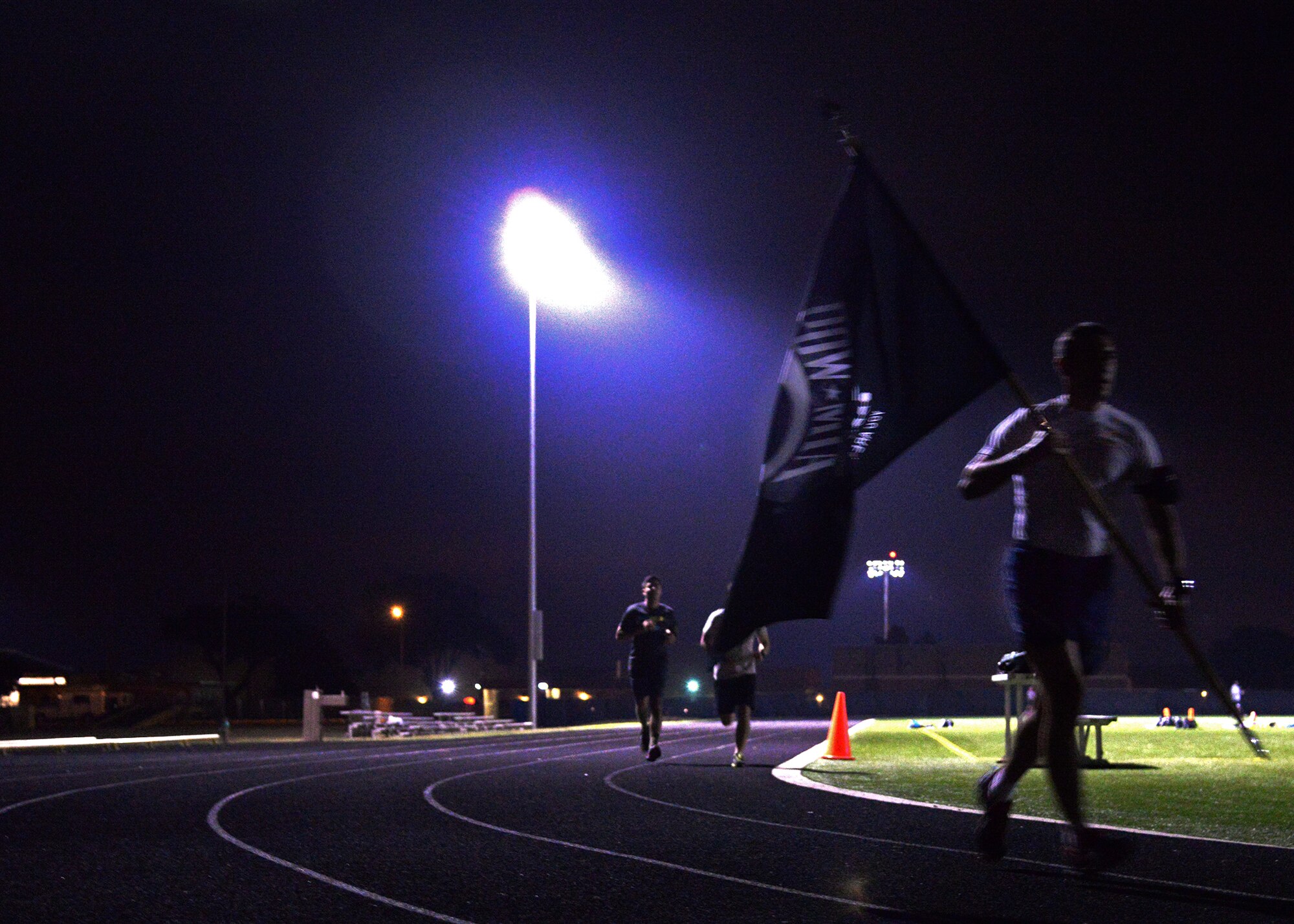 A lone Airman runs with the Prisoner of War/Missing in Action flag to pay tribute to POW/MIA men and women during a 24-hour vigil run Sept. 18, 2014 at Cannon Air Force Base, N.M. Air Commandos took turns running with the POW/MIA flag to honor the sacrifice that POW/MIA individuals have made for their nation. (U.S. Air Force photo/Airman 1st Class Chip Slack) 