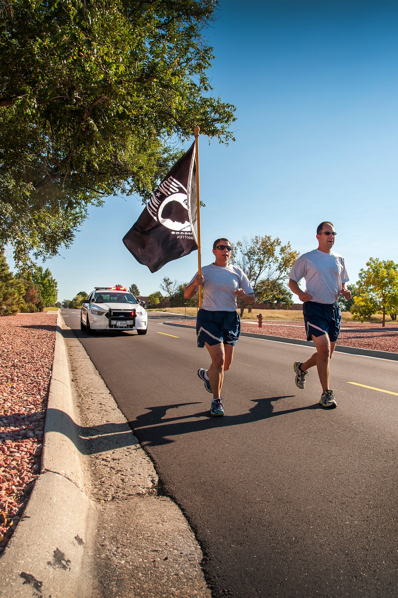 PETERSON AIR FORCE BASE, Colo. - Col. John Shaw, 21st Space Wing commander, and Chief Master Sgt. Idalia Peele, 21st SW command chief run with the POW flag following the POW/MIA recognition retreat ceremony Sept. 18. Members of the 21st SW held a reveille and retreat ceremony recognizing the sacrifices of POWs and MIAs. (U.S. Air Force photo/Craig Denton)