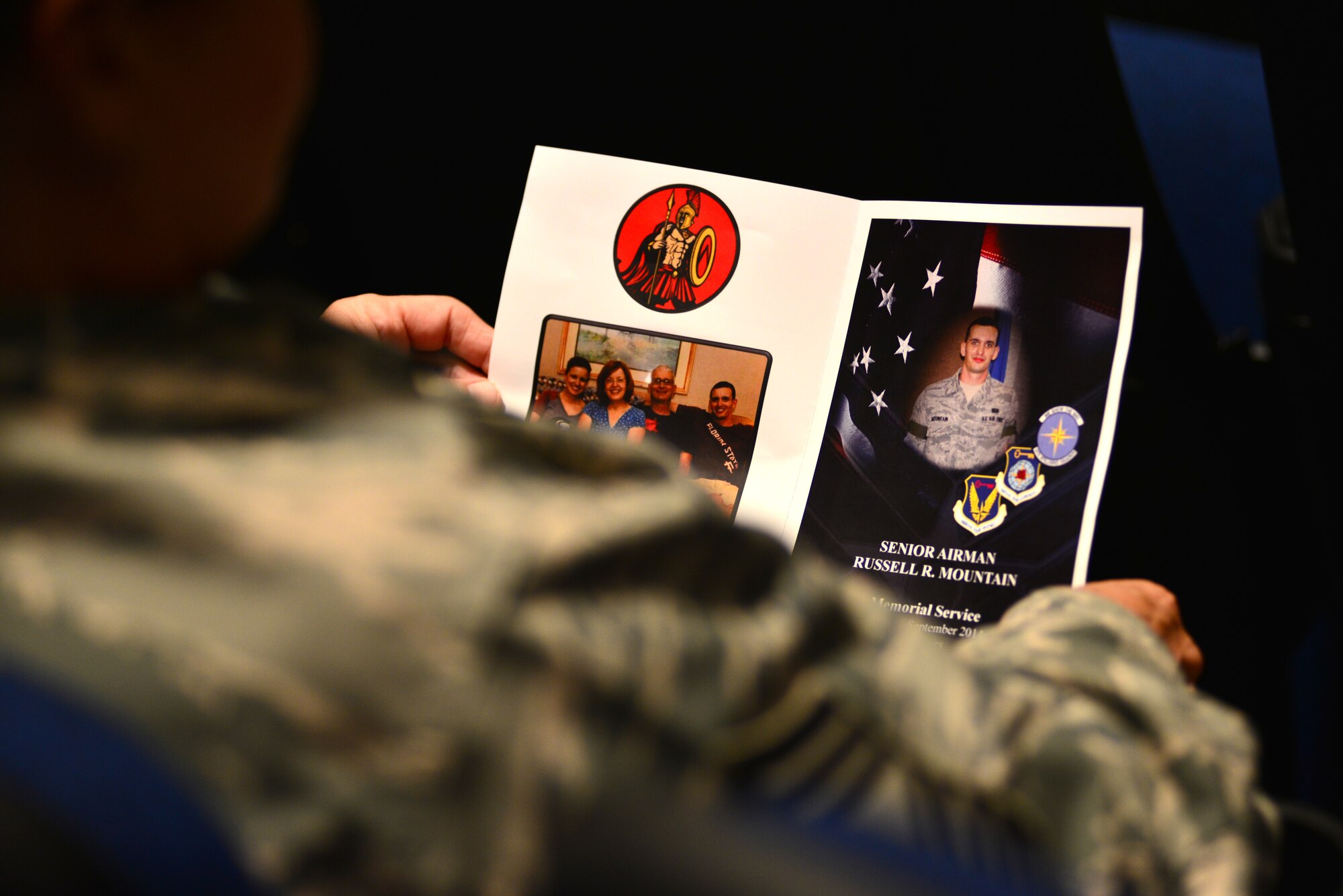 A U.S. Air Force Airman looks at a memorial program during a ceremony at Langley Air Force Base, Va., Sept. 19, 2014. The memorial ceremony was held in honor of Senior Airman Russell Mountain, a former 30th Intelligence Squadron analyst, who was killed in a motorcycle August 22. (U.S. Air Force photo by Senior Airman Aubrey White/Released) 