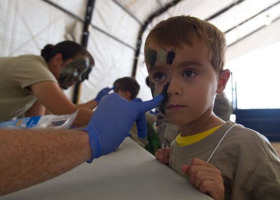 Team Holloman youth “deployer” 6-year-old Miles Rash, son of Capt. Kevin Rash, 49th Wing chaplain, gets his face painted during his chalk walk for Operation Kids Investigating Deployment at Holloman Air Force Base N.M., Sept. 22. Operation K.I.D. is an event put on for military youth that teaches them the deployment process. Youth ages 5-13 go through a mock deployment at the 49th Materiel Maintenance Group and receive military orders, gear and a uniform. The children also learn about safety and the conditions of their mock destination. This annual event is held to give kids a better understanding on what it’s like when their loved ones prepare for deployment. (U.S. Air Force photo by Senior Airman Leah Ferrante/Released)