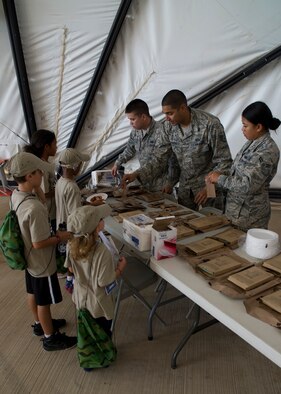 Team Holloman youth “deployers” walk through chalks and pick up a Meal-Ready-to-Eat during Operation Kids Investigating Deployment at Holloman Air Force Base N.M., Sept. 22. The kids got to eat and test the different kinds of MRE’s, seeing what food is like in some deployed locations. Operation K.I.D. is an event put on for military youth that teaches them the deployment process. Youth ages 5-13 go through a mock deployment at the 49th Materiel Maintenance Group and receive military orders, gear and a uniform. The children also learn about safety and the conditions of their mock destination. This annual event is held to give kids a better understanding on what it’s like when their loved ones prepare for deployment. (U.S. Air Force photo by Senior Airman Leah Ferrante/Released) 