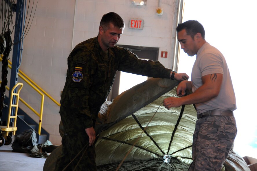 Lithuanian Air Force Sgt. Darius Dabužinskas assists U.S. Air Force Tech. Sgt. Brian Sommers, aerial transportation specialist assigned to the 193rd Special Operations Logistics Readiness Squadron during a parachute rigging demonstration, Sept. 19, 2014 at Middletown, Pa. This was during training that members of the Lithuanian Air Force and a member of the Latvian Air Force, attended as part of Pennsylvania-Lithuania National Guard State Partnership Program. (U.S. Air National Guard photo by Tech. Sgt. Culeen Shaffer/Released)