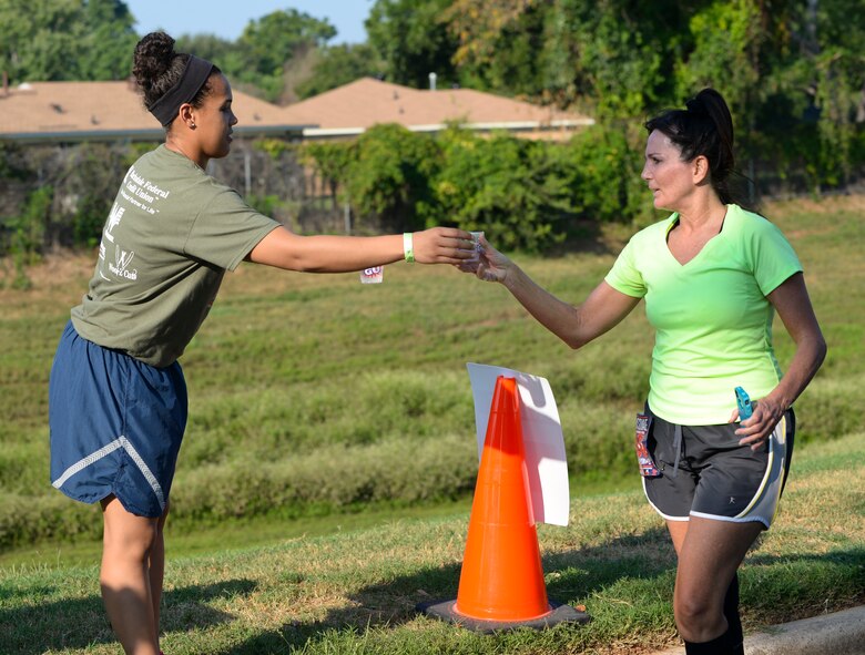 A volunteer gives a cup of water to a runner during the half-marathon and 5k run on Barksdale Air Force Base, La., Sept. 20, 2014. Tables were set up every few miles to allow runners to rehydrate during the run. (U.S. Air Force photo/Airman 1st Class Benjamin Raughton)