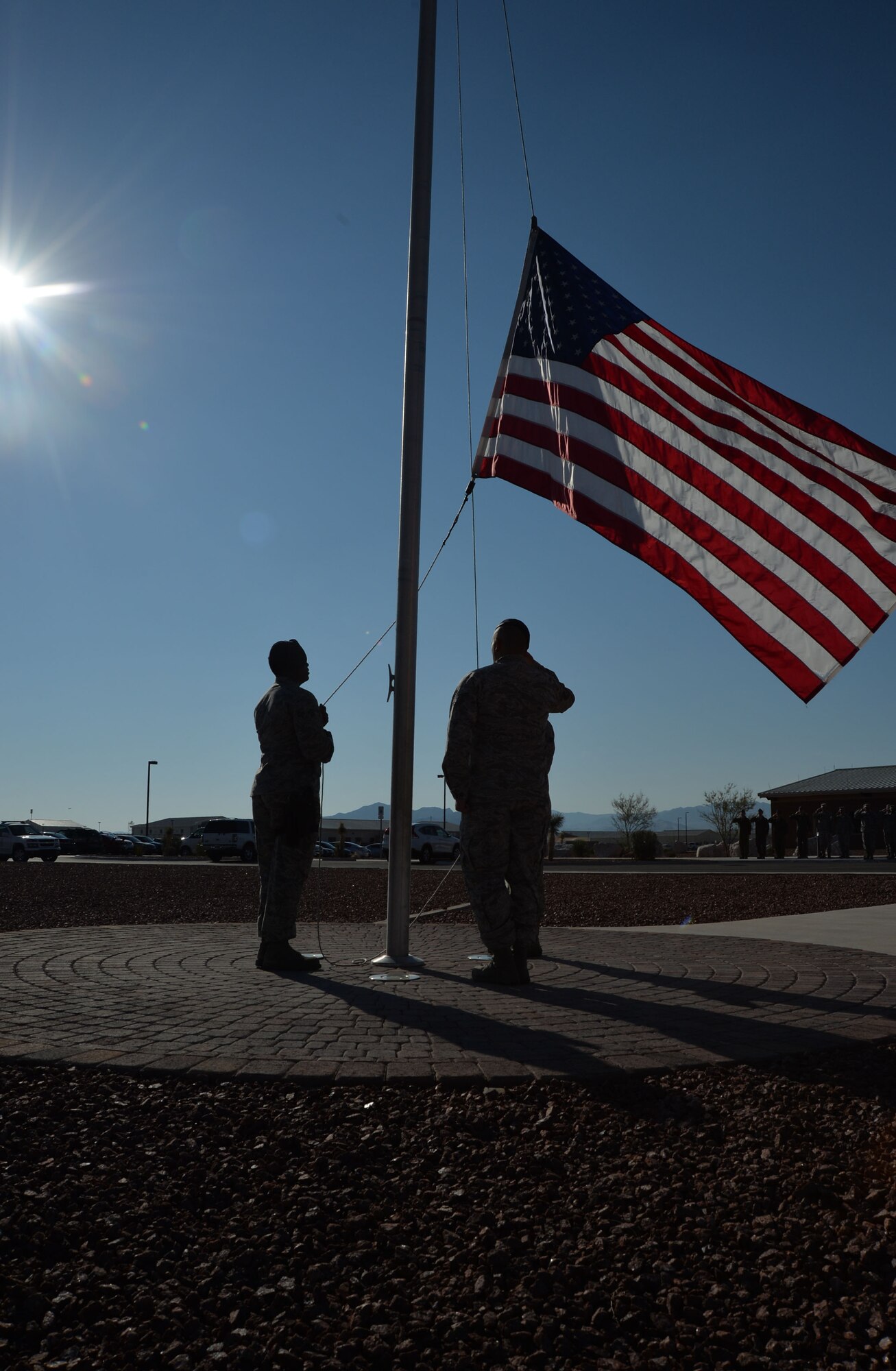 Airmen from the 799th Security Forces Squadron lower the flag during a formal retreat ceremony in remembrance of 9/11 at Creech Air Force Base, Nevada, Sept. 11, 2014. The event took place to honor those lost on Sept. 11, 2001, and those who have paid the ultimate sacrifice in the defense of our country. (U.S. Air Force photo by Tech. Sgt. Nadine Barclay/RELEASED)