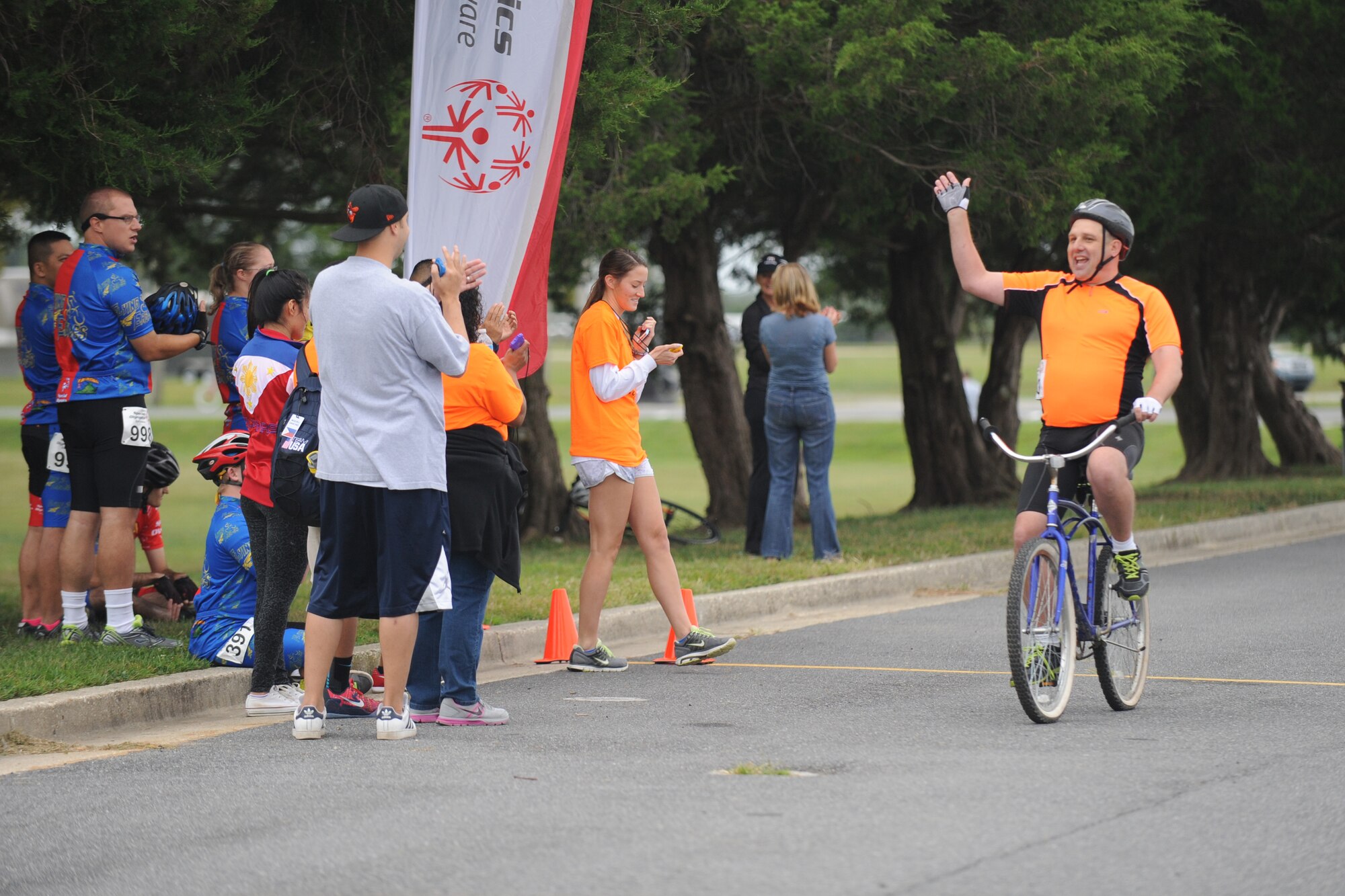 A Special Olympics of Delaware Cycling Competition athlete waves at supporters as he passes the finish line Sept. 13, 2014 at Dover Air Force Base, Del. The Special Olympics are held for children and adults with intellectual disabilities. (U.S. Air Force photo/Staff Sgt. Elizabeth Morris)
