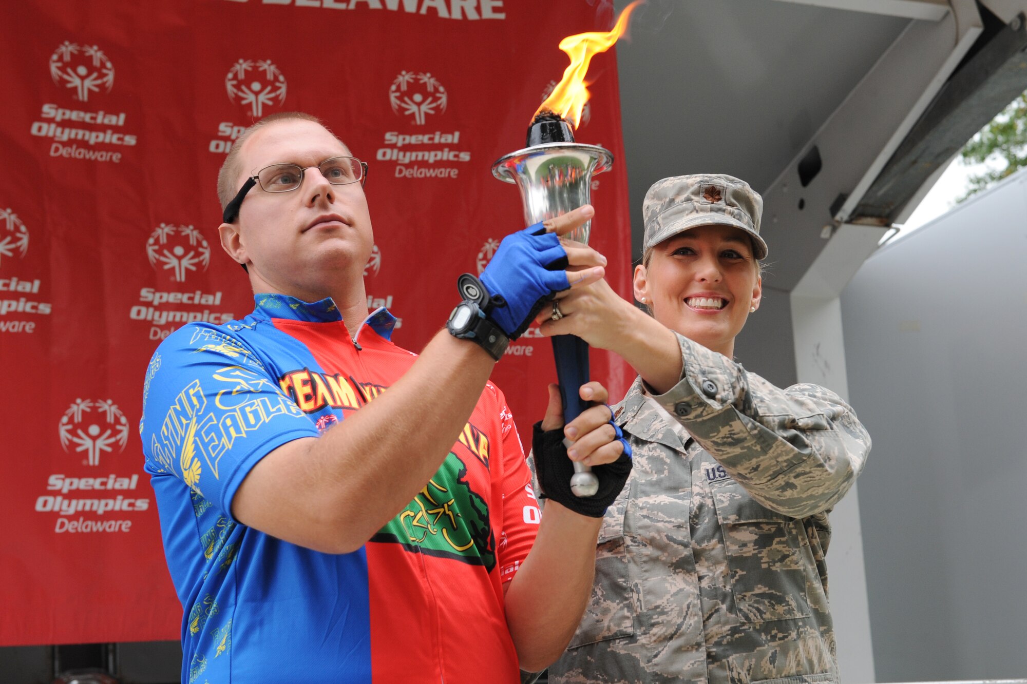 Maj. Rayna Lowery, 436th Logistics Readiness Squadron commander, passes the Special Olympics torch to Bobby Opiela, Special Olympics athlete from the Virginia team, during the Special Olympics of Delaware Cycling CompetitionSept. 13, 2014 at Dover Air Force Base, Del. Lowery was at the competition to officially proclaim the games open. (U.S. Air Force photo/Staff Sgt. Elizabeth Morris)