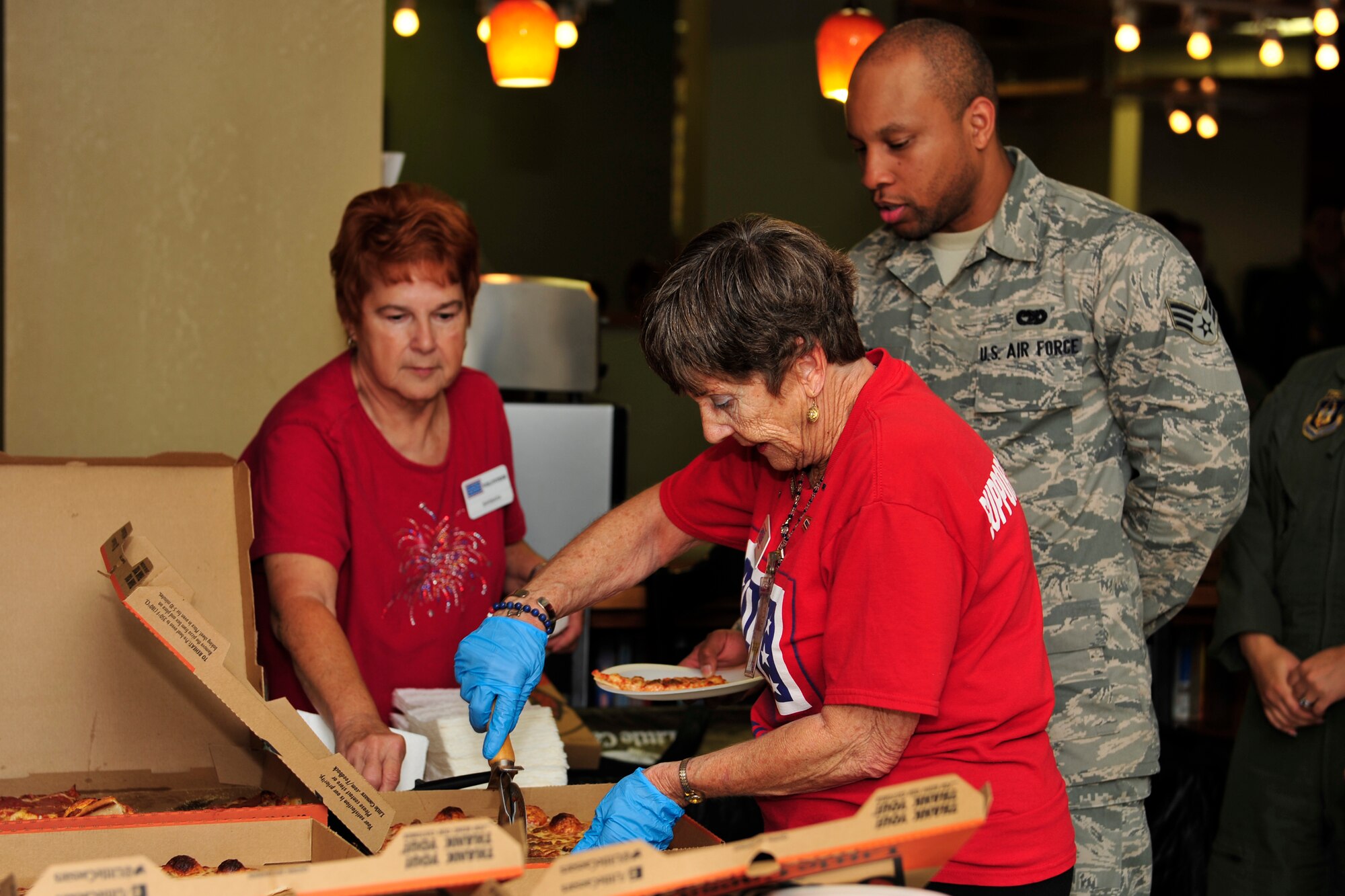 Barbara Morton and Rose Hirth, USO volunteers, serve pizza to Team Dover members during the Air Force's 67th Birthday celebration Sept. 18, 2014 at the USO lounge on Dover Air Force Base, Del. The event was paid for by a national sponsor of the USO. (U.S. Air Force photo/Staff Sgt. Elizabeth Morris)