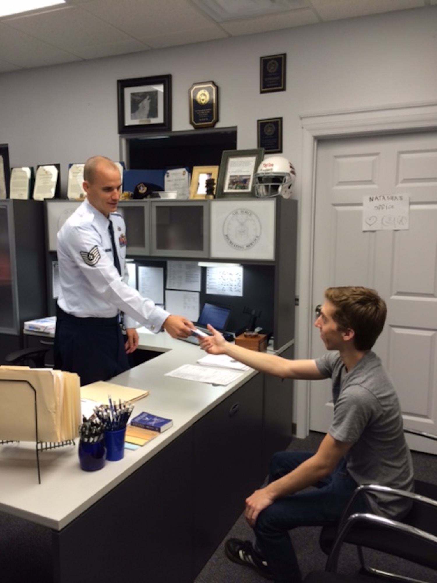 Tech. Sgt. Ryan Cole, 317th Recruiting Squadron Line Officer Accessions recruiter, hands an applicant a business card at his recruiting office in Waldorf, Md. (U.S. Air Force photo)
