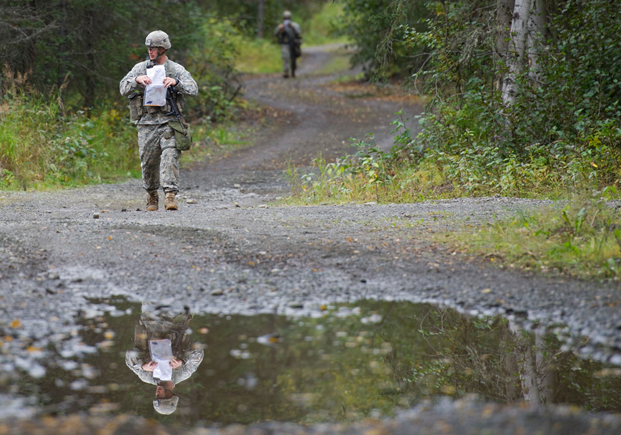Army Capt. Edward Blyth, a native of Yorktown, Va., assigned to Dog Company, 3rd Battalion (Airborne), 509th Infantry Regiment, 4th Infantry Brigade Combat Team (Airborne), 25th Infantry Division, U.S. Army Alaska, is seen reflected in a pool of rain water as he walks to point on the land navigation course during Expert Infantryman Badge qualification on Joint Base Elmendorf-Richardson, Tuesday, Sept. 9, 2014. The Expert Infantryman Badge was approved by the Secretary of War on October 7, 1943, and is currently awarded to U.S. Army personnel who hold infantry or special forces military occupational specialties and successfully pass the rigors of the course. (U.S. Air Force photo/Justin Connaher)