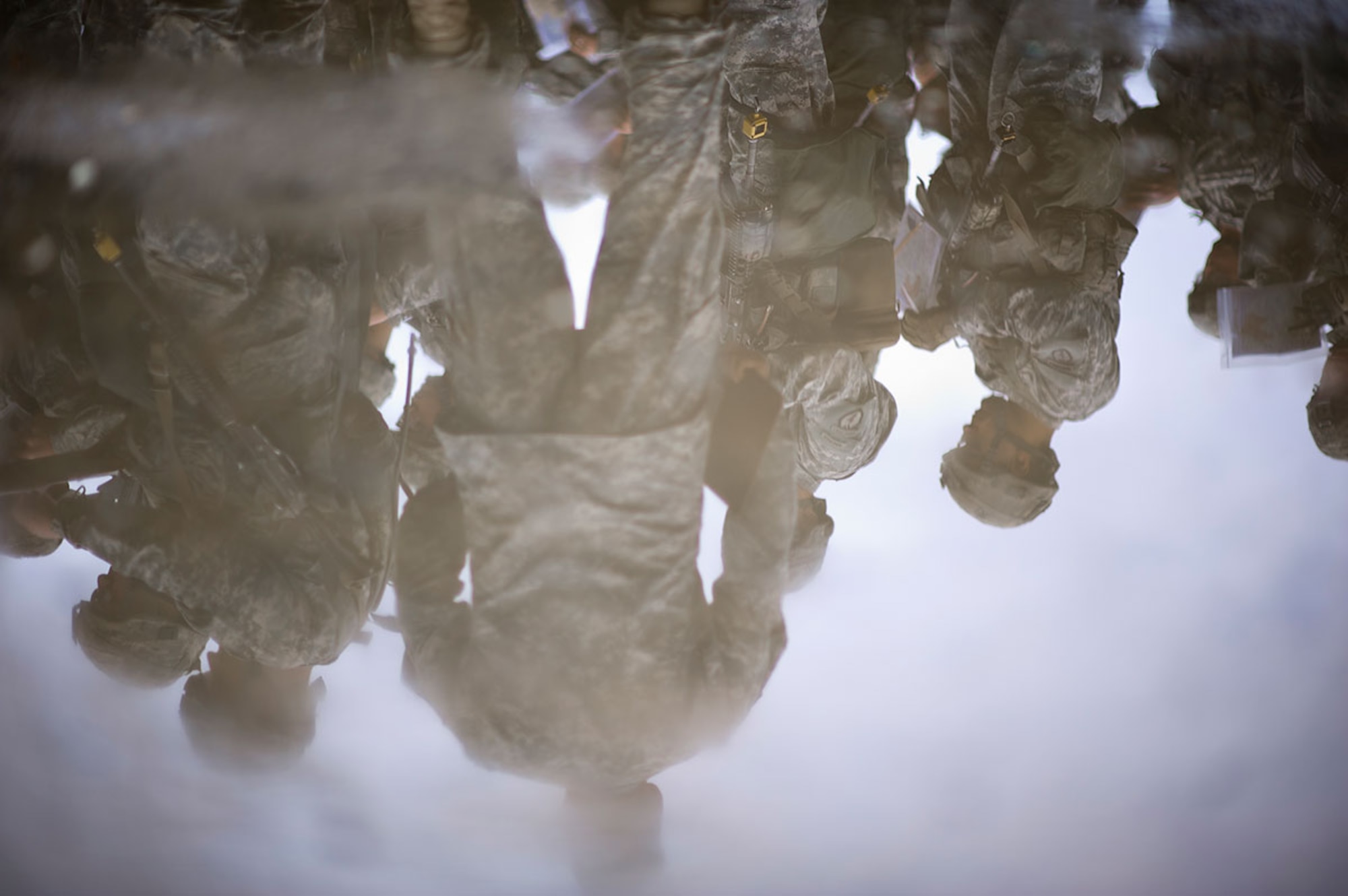 Parachute infantrymen assigned to U.S. Army Alaska's 4th Infantry Brigade Combat Team (Airborne), 25th Infantry Division, are seen reflected in a pool of rain water as they prepare to test on the land navigation course during Expert Infantryman Badge qualification on Joint Base Elmendorf-Richardson, Tuesday, Sept. 9, 2014. The Expert Infantryman Badge was approved by the Secretary of War on October 7, 1943, and is currently awarded to U.S. Army personnel who hold infantry or special forces military occupational specialties and successfully pass the rigors of the course. (U.S. Air Force photo/Justin Connaher)