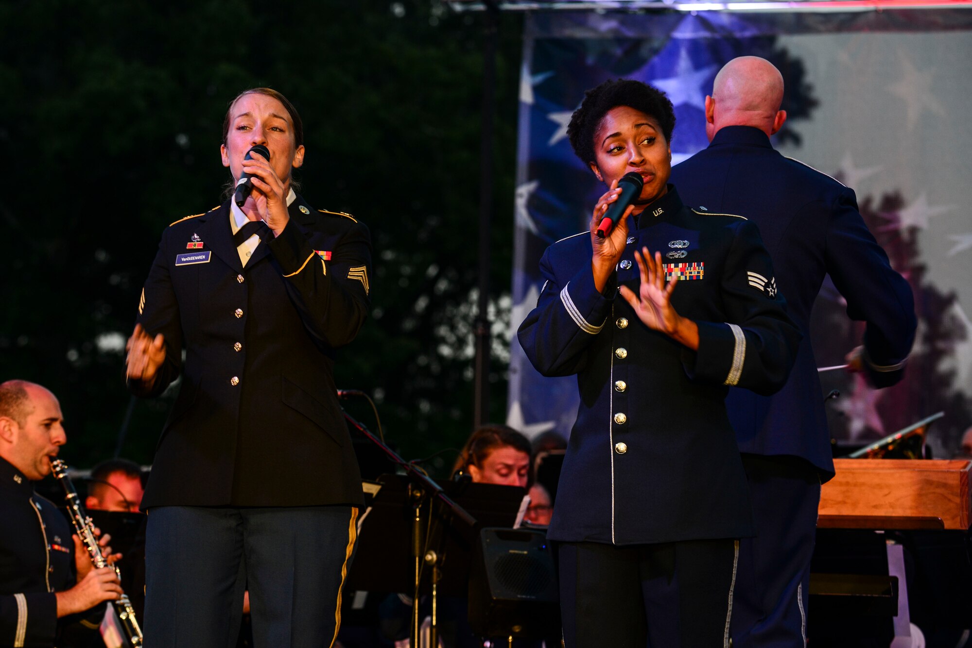 U.S. Army Sgt. Megan Van Oudenaren, Training and Doctrine Command Band vocalist, and U.S. Air Force Senior Airman Emerald Payne, U.S Air Force Heritage of America Band vocalist, perform during the Constitution Day “Support and Defend” concert at Williamsburg, Va., Sept 17, 2014. The vocalists encouraged the crowd to join them in singing along with songs including “God Bless America” and “You’re A Grand Old Flag.” (U.S. Air Force photo by Airman 1st Class Kimberly Nagle/Released)