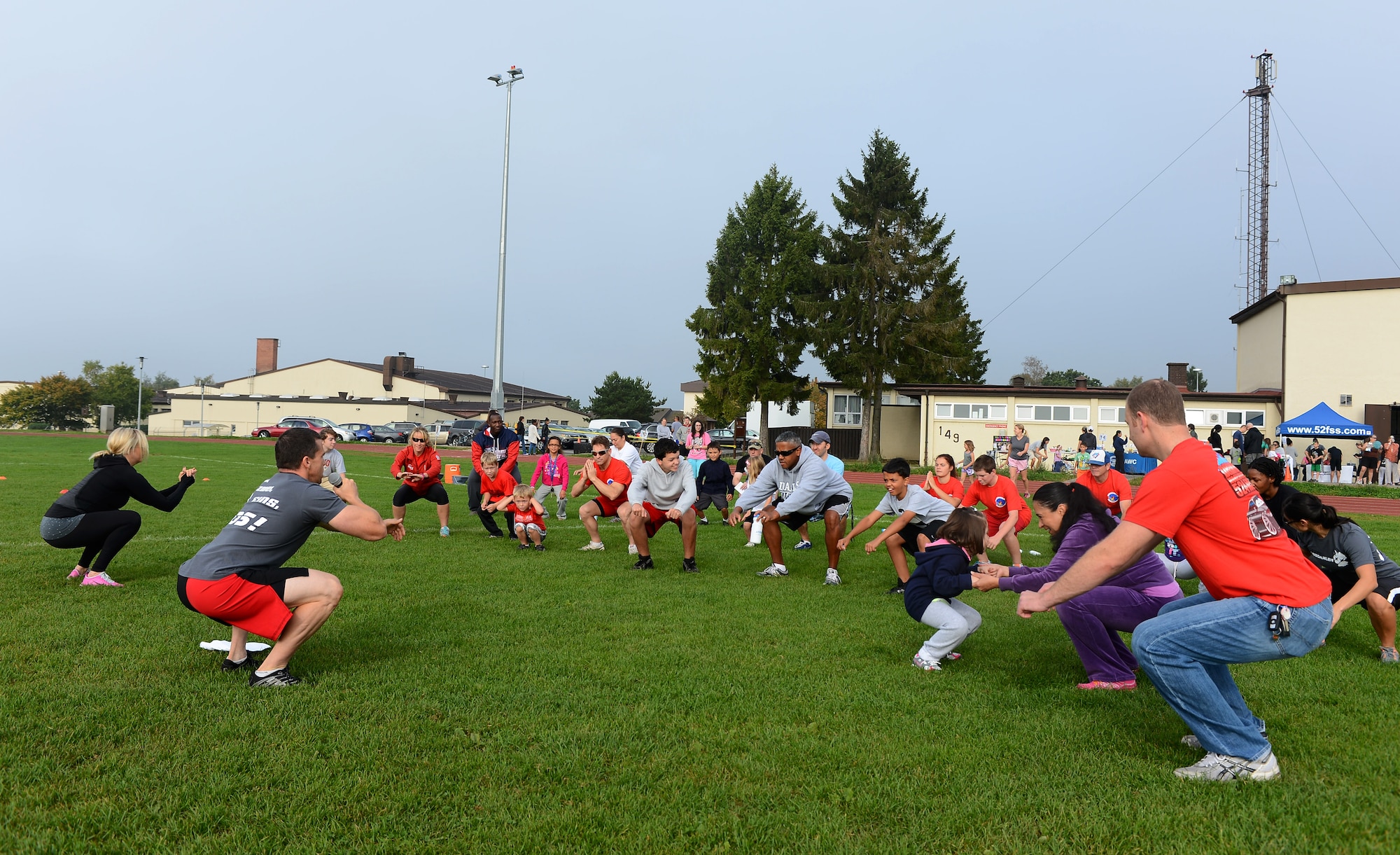 Families gather together to stretch out before the start of Fit Family Field Day at the outdoor track and field on Spangdahlem Air Base, Germany, Sept. 20, 2014. The event lasted two hours and provided families with nutrition and health information in addition to the workouts they performed. (U.S. Air Force photo by Airman 1st Class Luke J. Kitterman/Released)